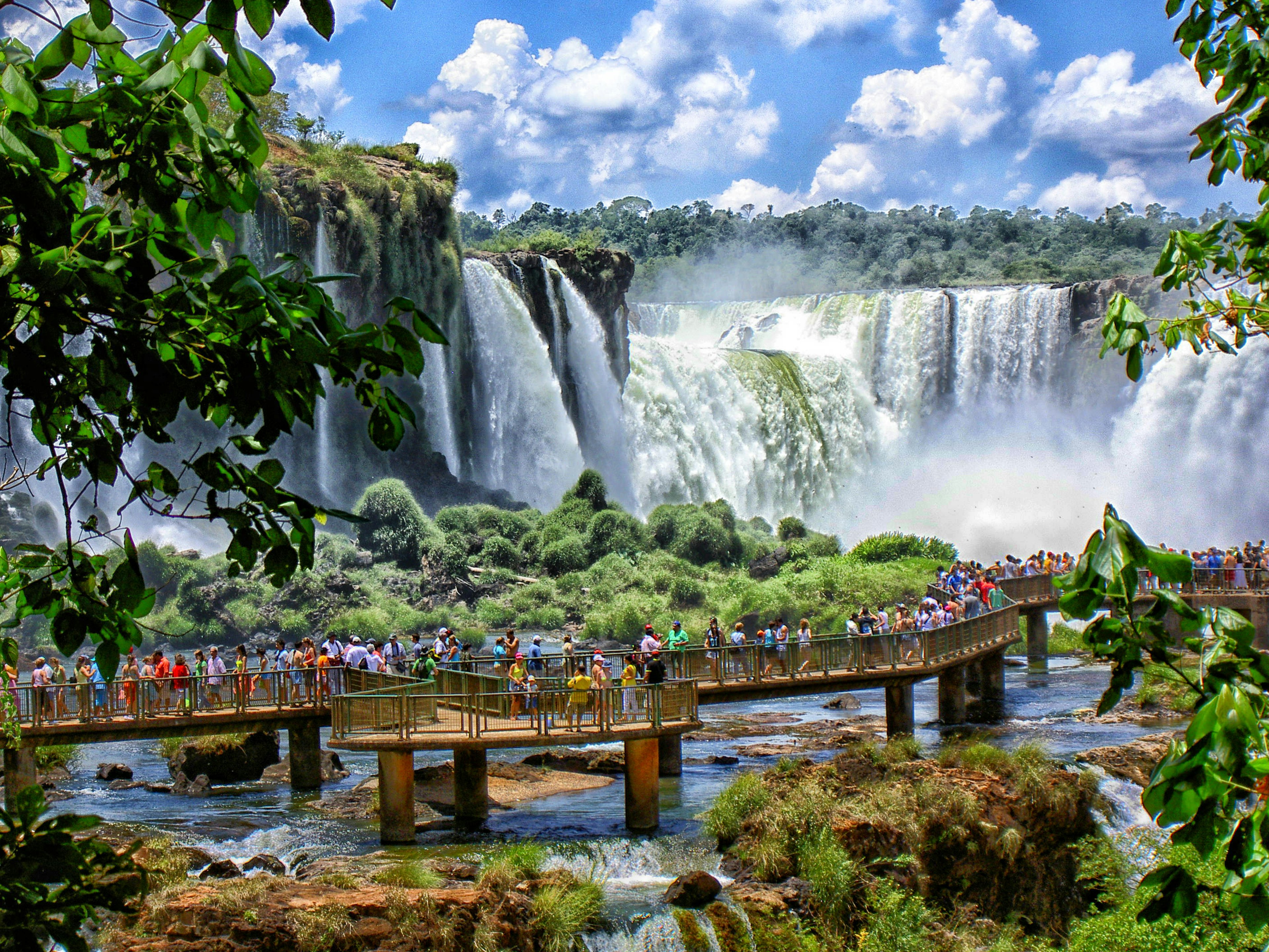 Visitors on a boardwalk admiring a vast network of waterfalls