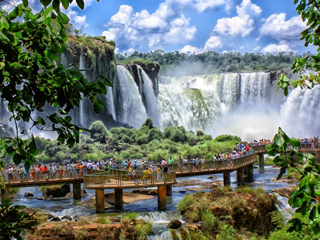 Visitors on a boardwalk admiring a vast network of waterfalls