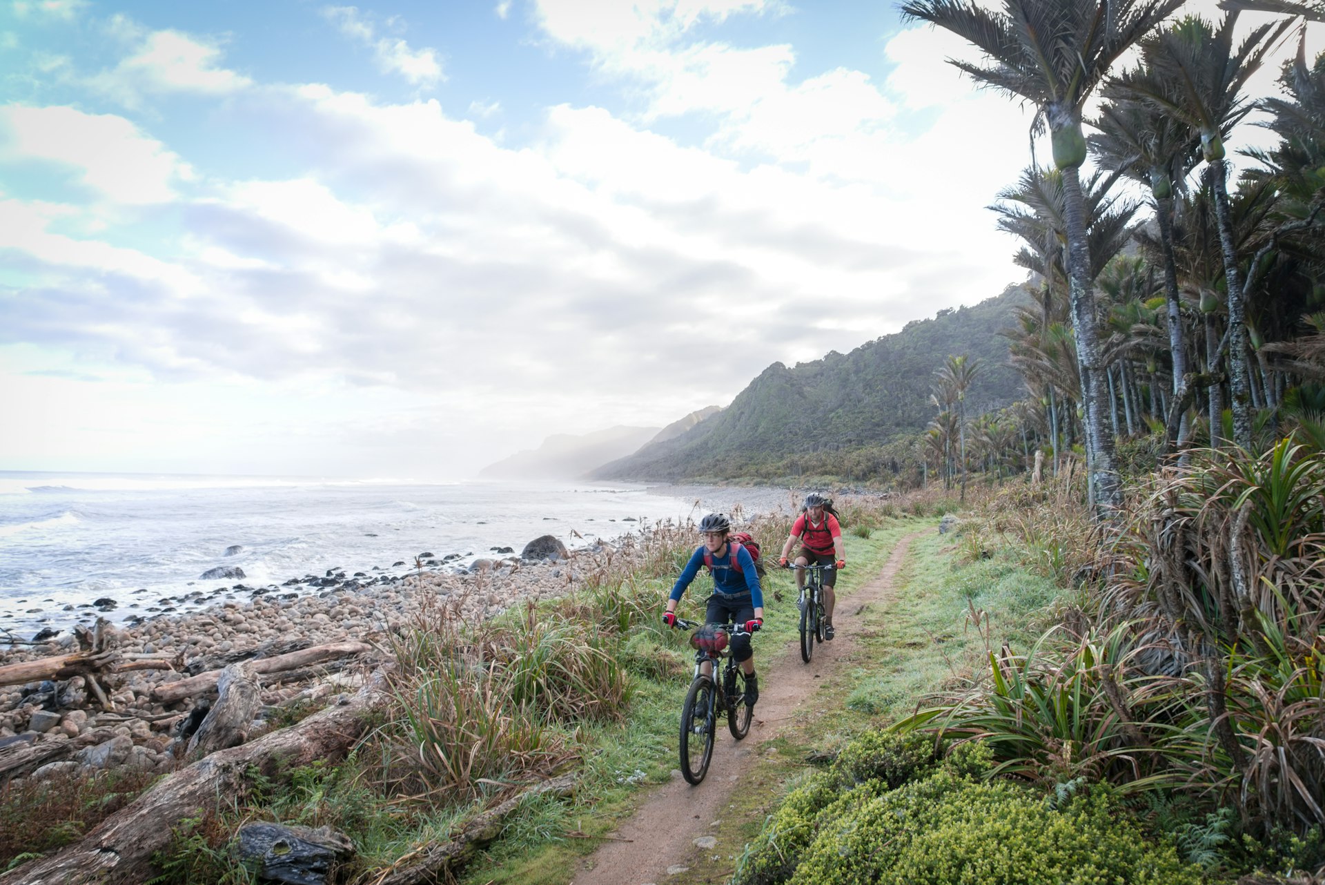 Two mountain-bikers ride along a coastal trail