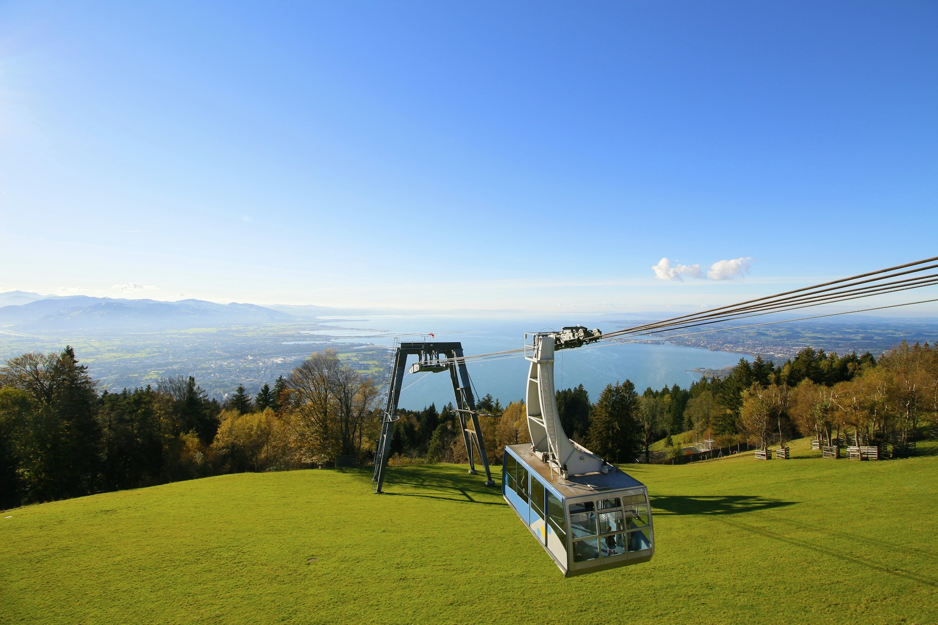 A cable car rises with the massive Lake Constance in the background. 