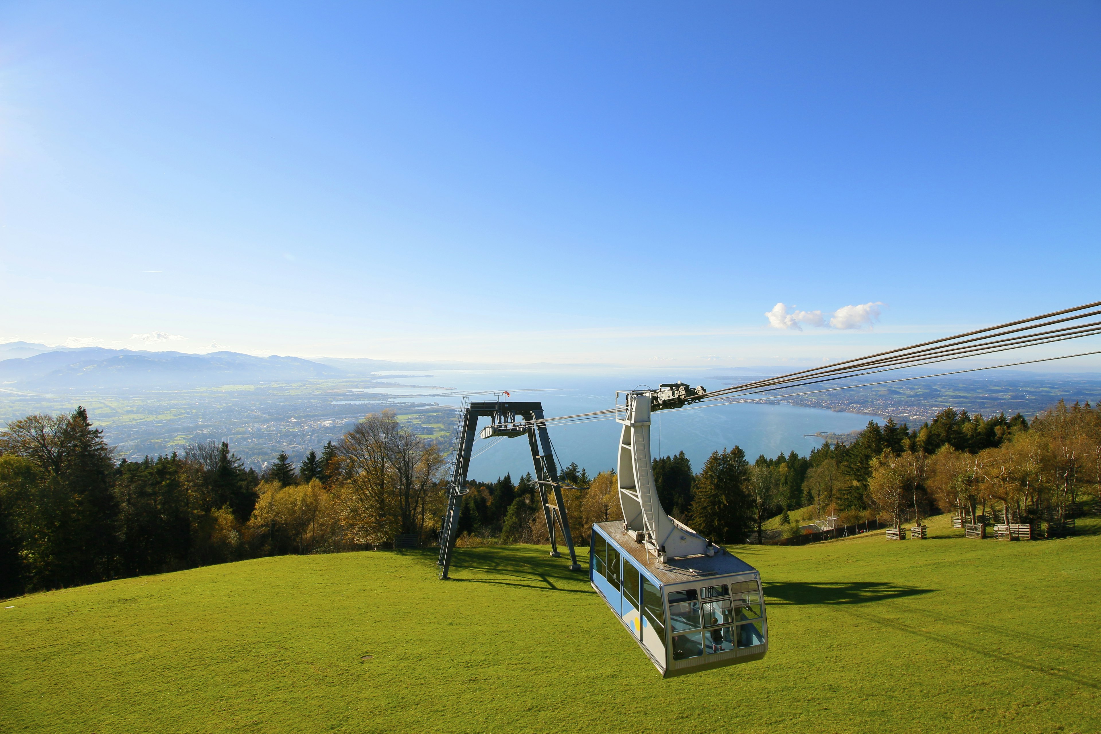 A cable car rises with the massive Lake Constance in the background