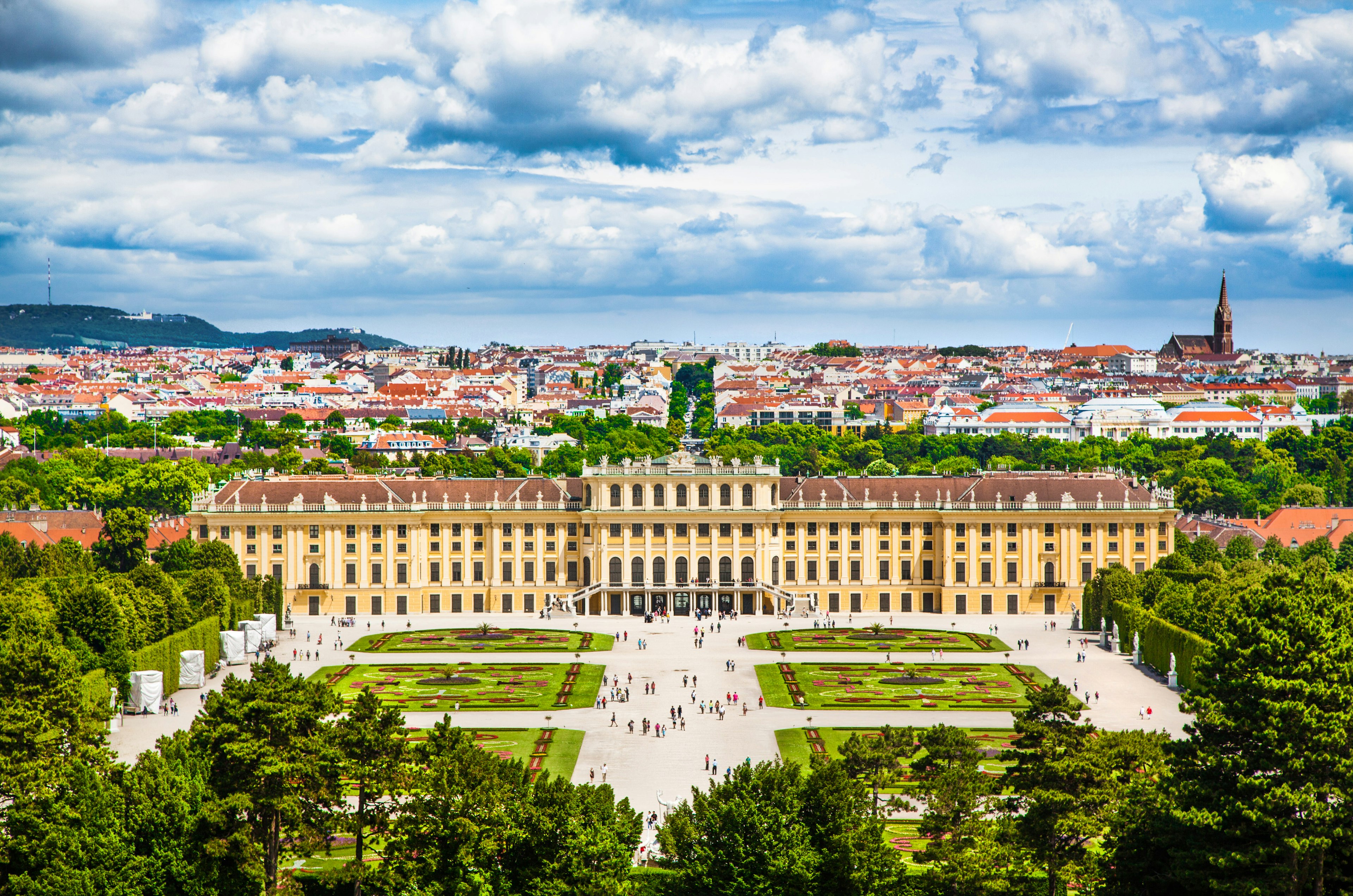 A palace courtyard viewed from above with people milling around the lawns