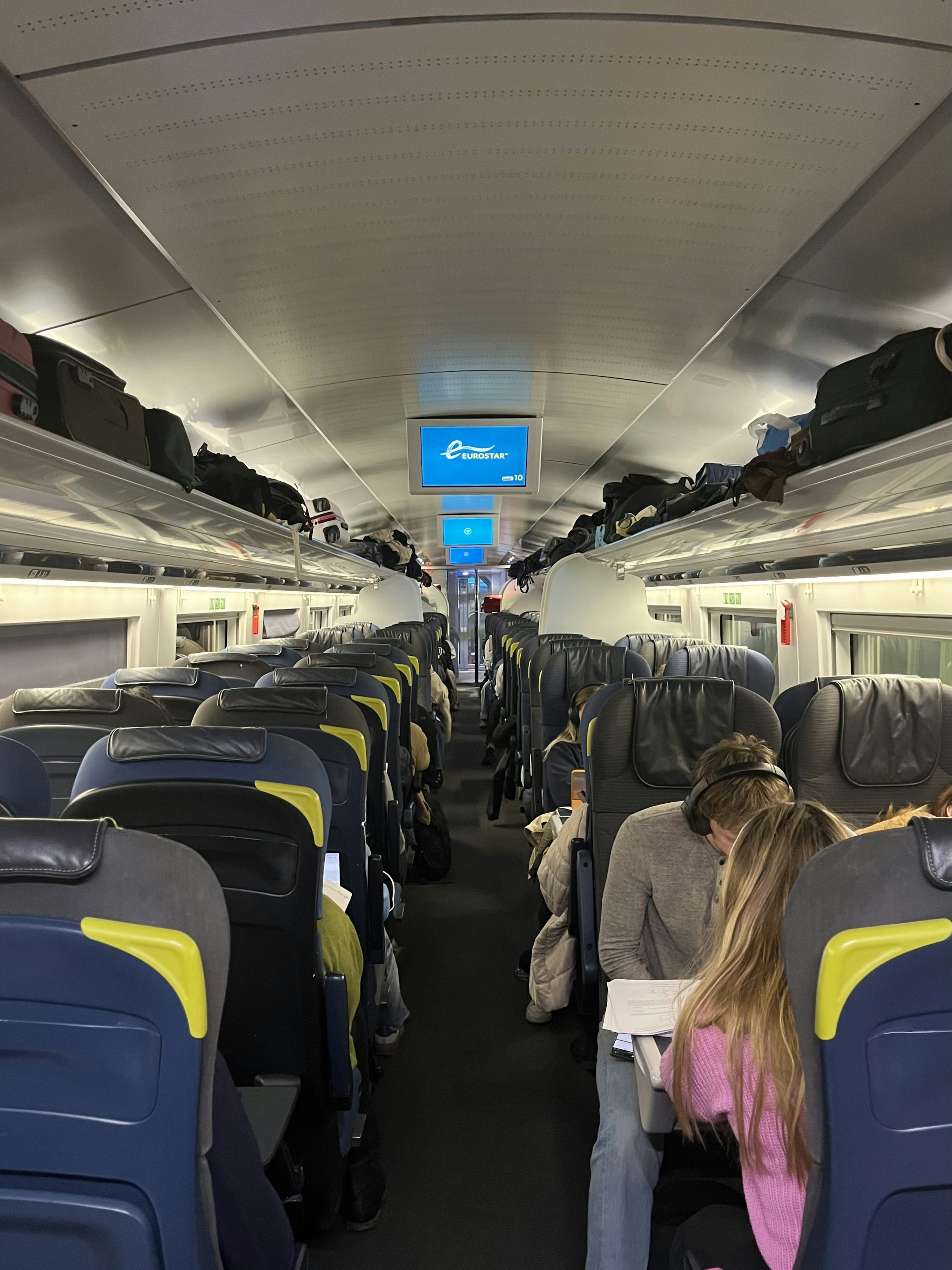 A carriage on a train with seats in a two-by-two formation and an aisle in the center