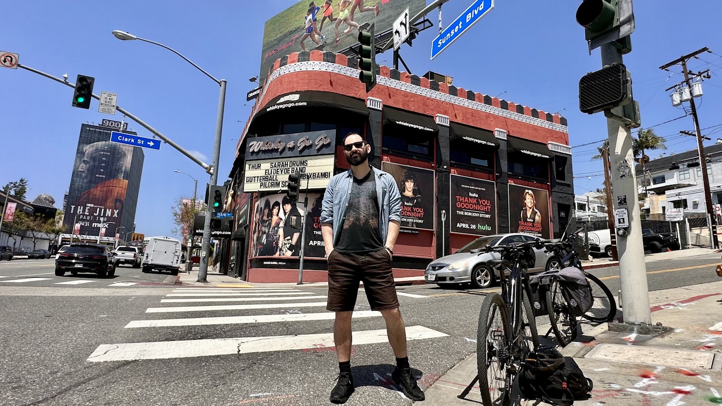 Writer James March stands in front of a bike during a sunny day in front of of Whiskey a Go Go on the Sunset Strip