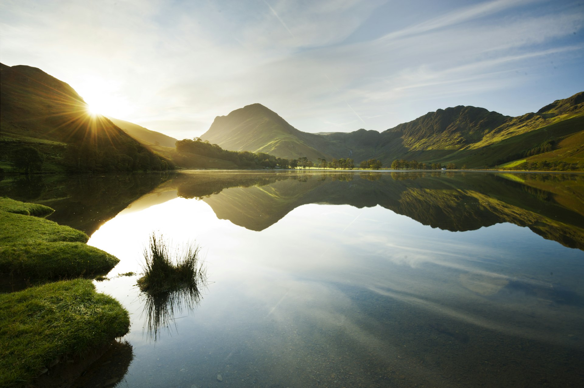 Light shines over the rustic hills above a lake in England's Lake District. 