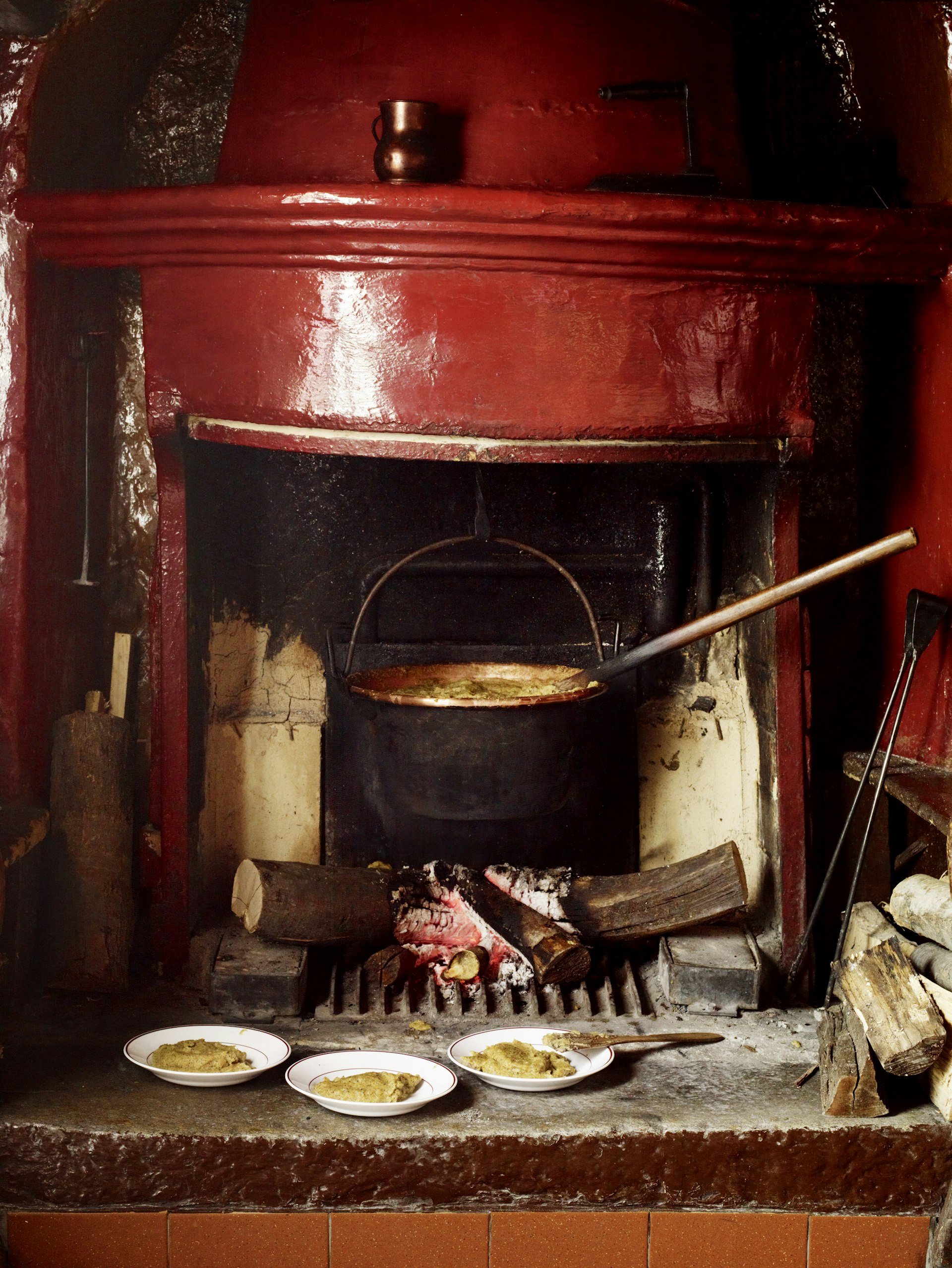 Polenta cooking over a fire in a red fireplace