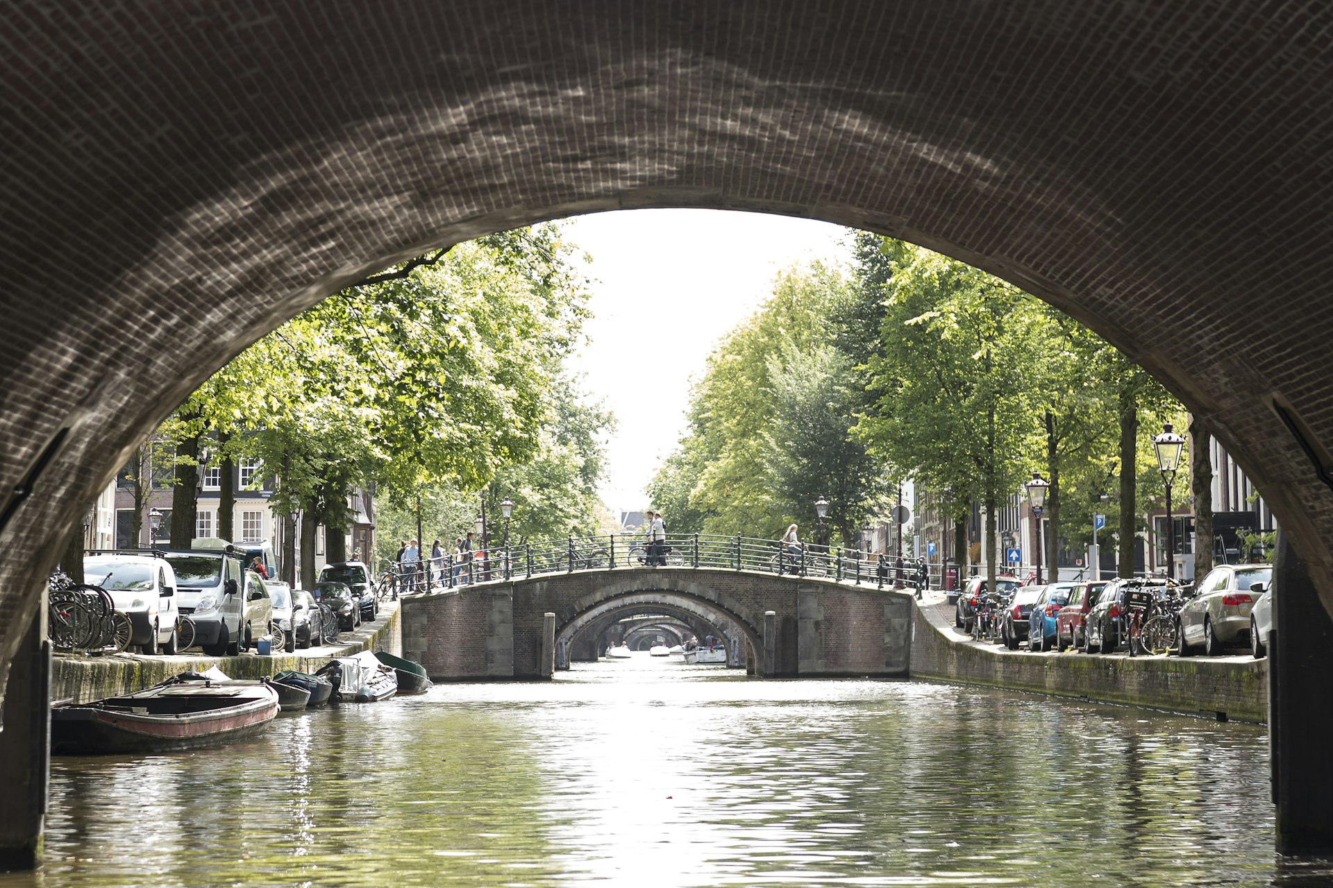A view from underneath a bridge shows the canals and bridges of Amsterdam. 