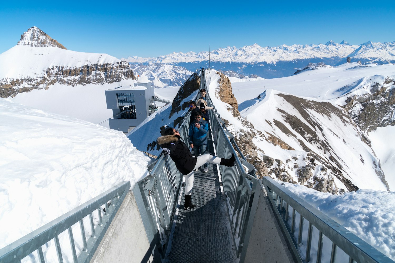 Unidentified tourists walk and capture on Titlis Cliff Walk, suspension bridge at Mount Titlis in Engelberg, Switzerland ; 