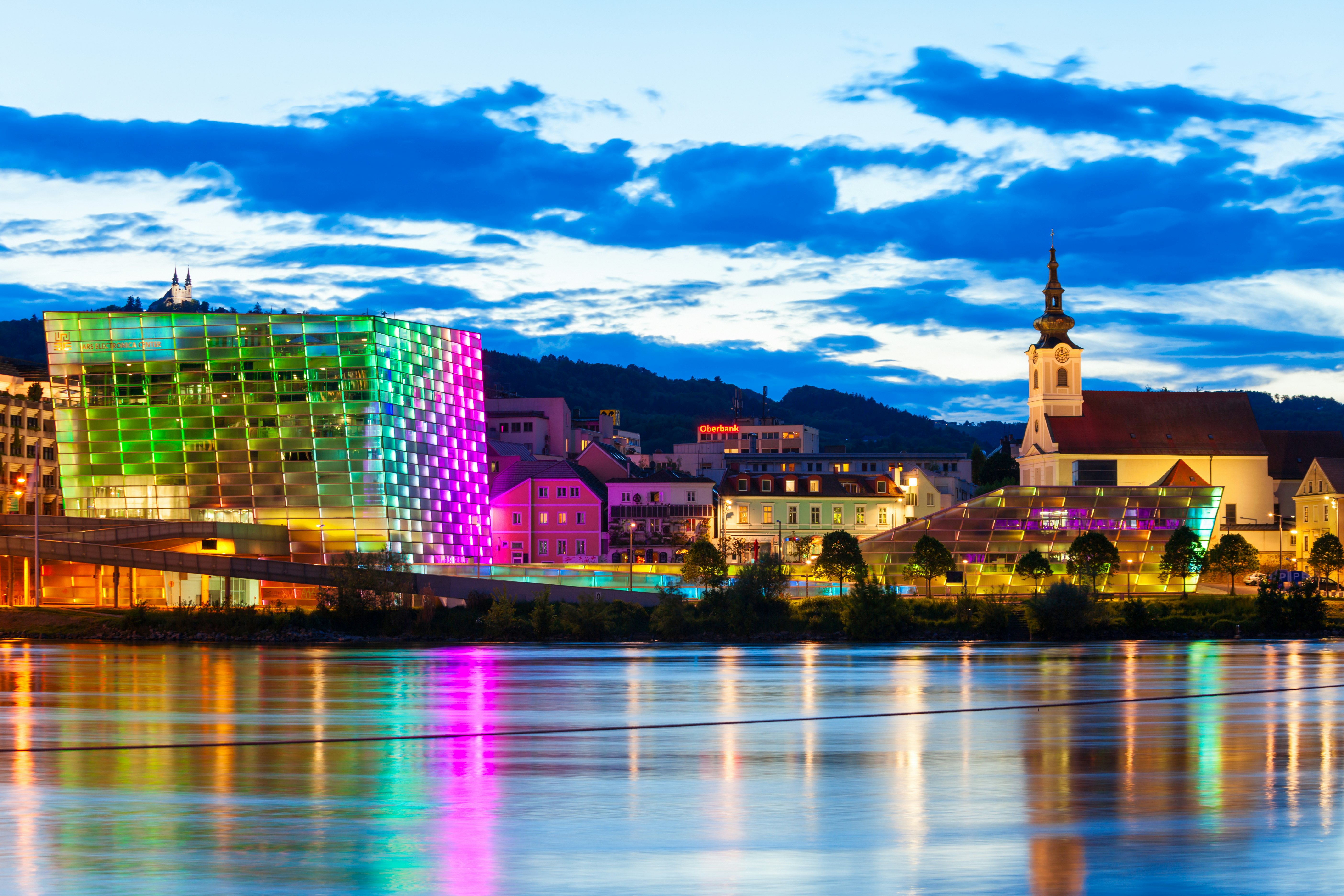 A riverside museum building near a river lit up at night