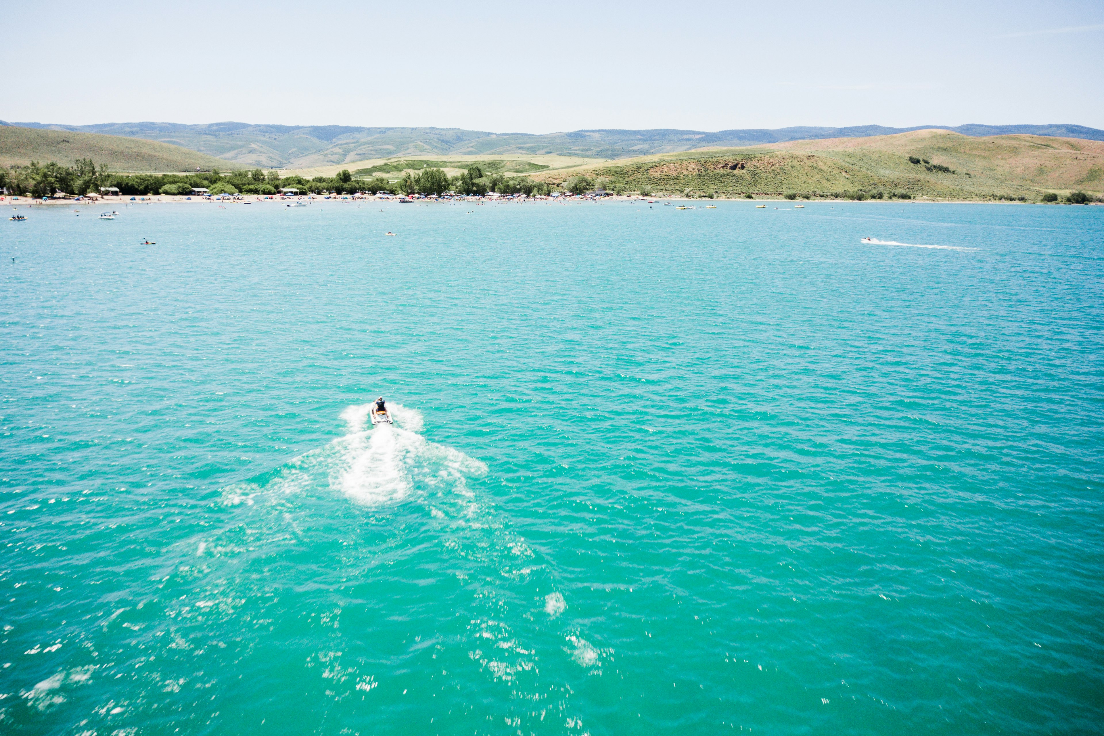 An aerial shot of a boat crossing the blue waters of Bear Lake at the Utah-Idaho border