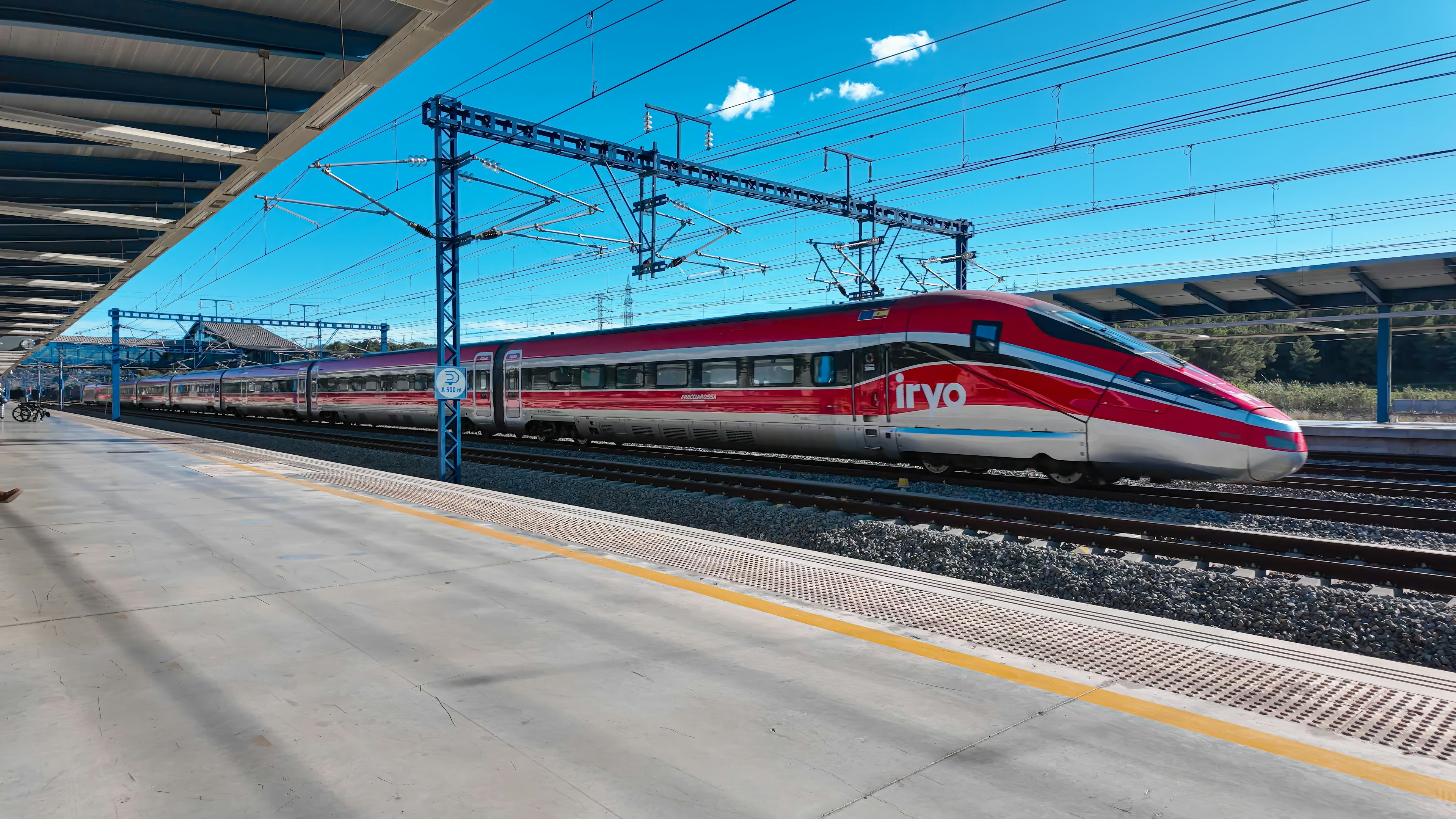 A red train speeds through a station