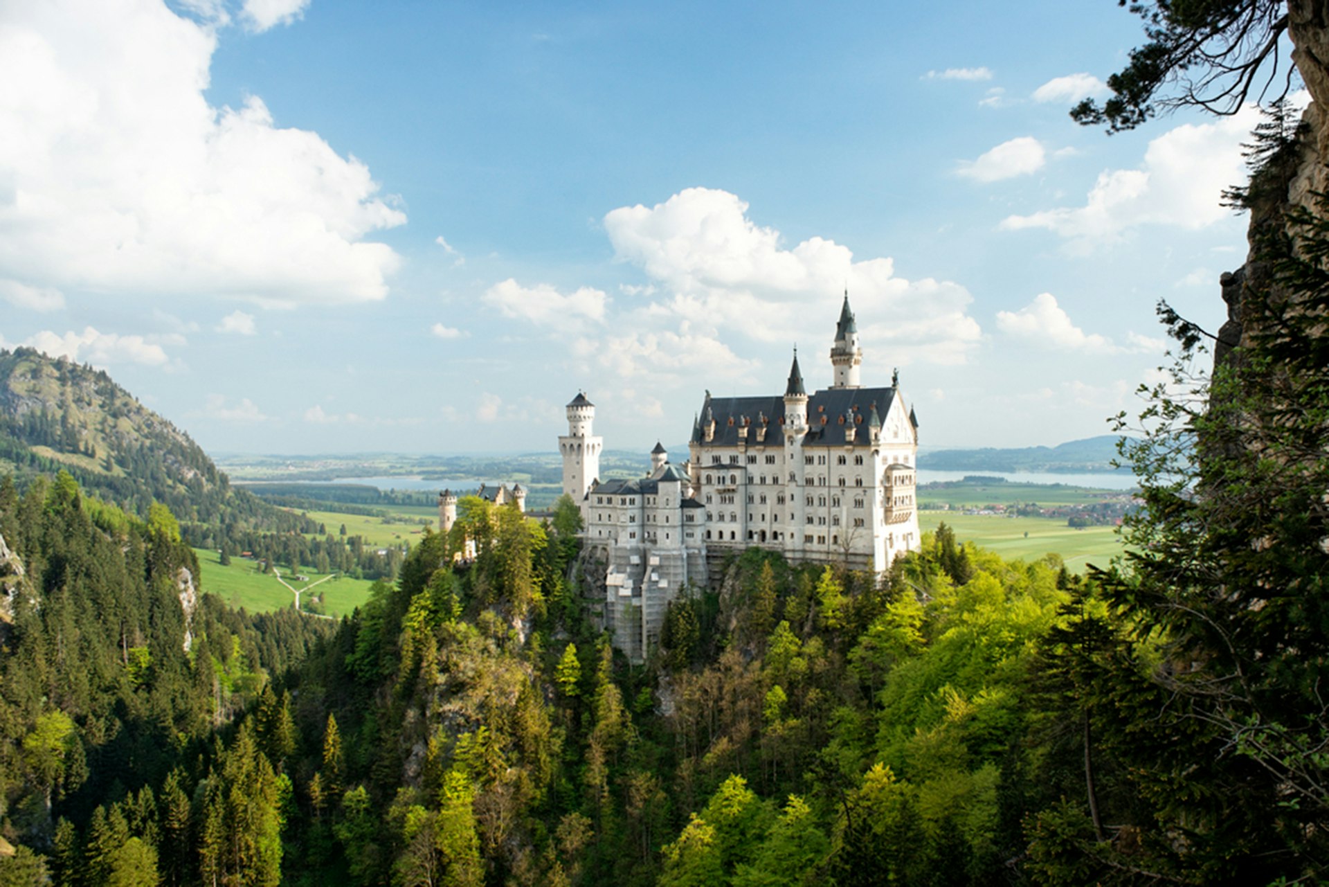 A fairytale-style castle rises from lush green hills in Bavaria, Germany. 