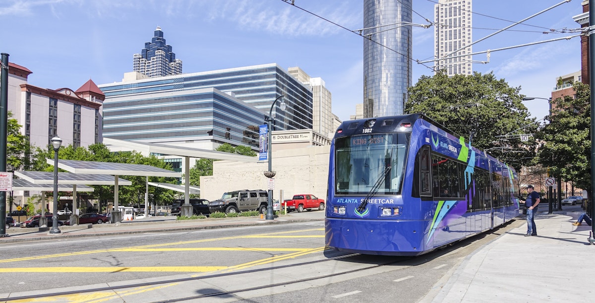 The Atlanta Streetcar sits at Olympic Park Station with the city in the background