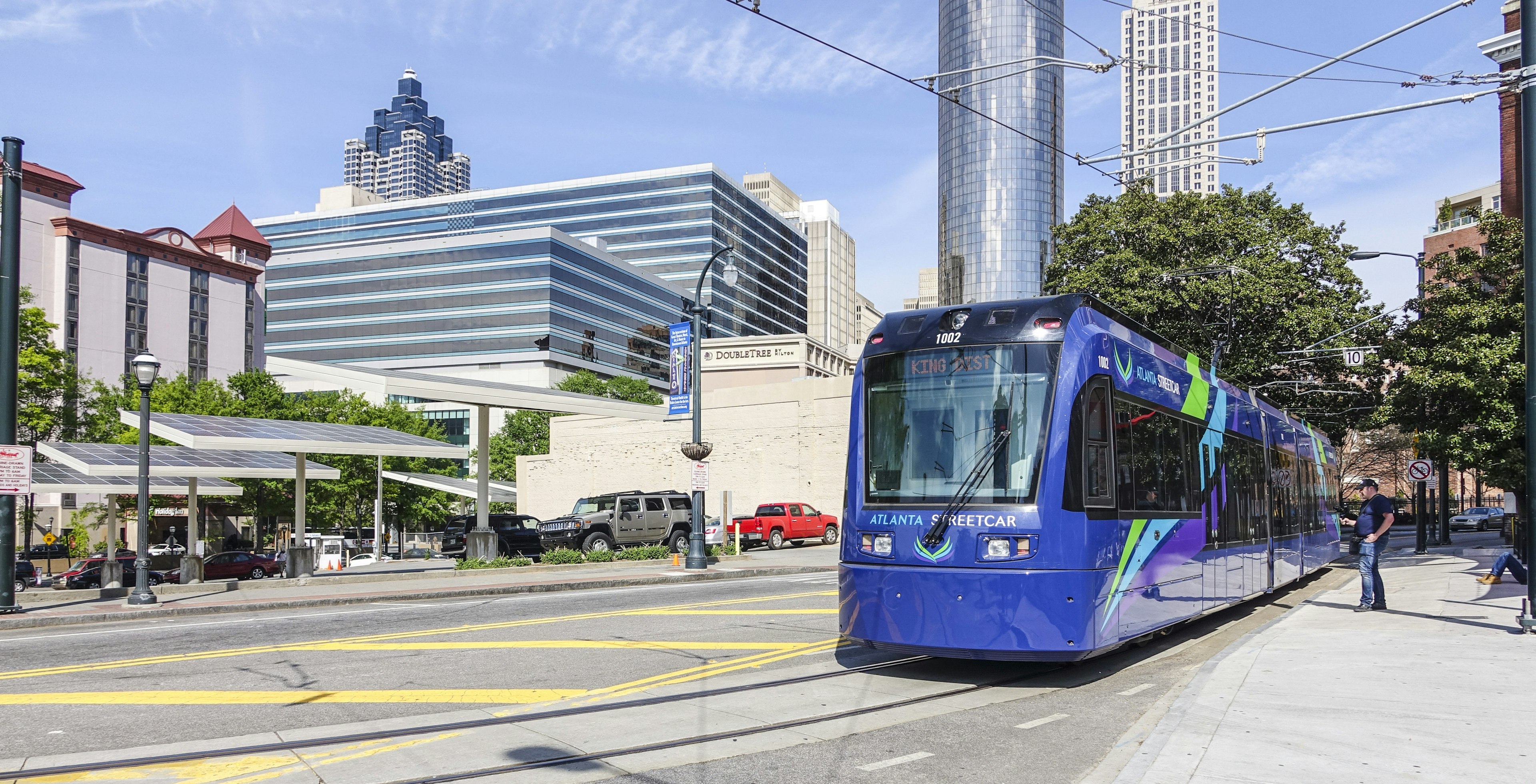 The Atlanta Streetcar sits at Olympic Park Station with the city in the background