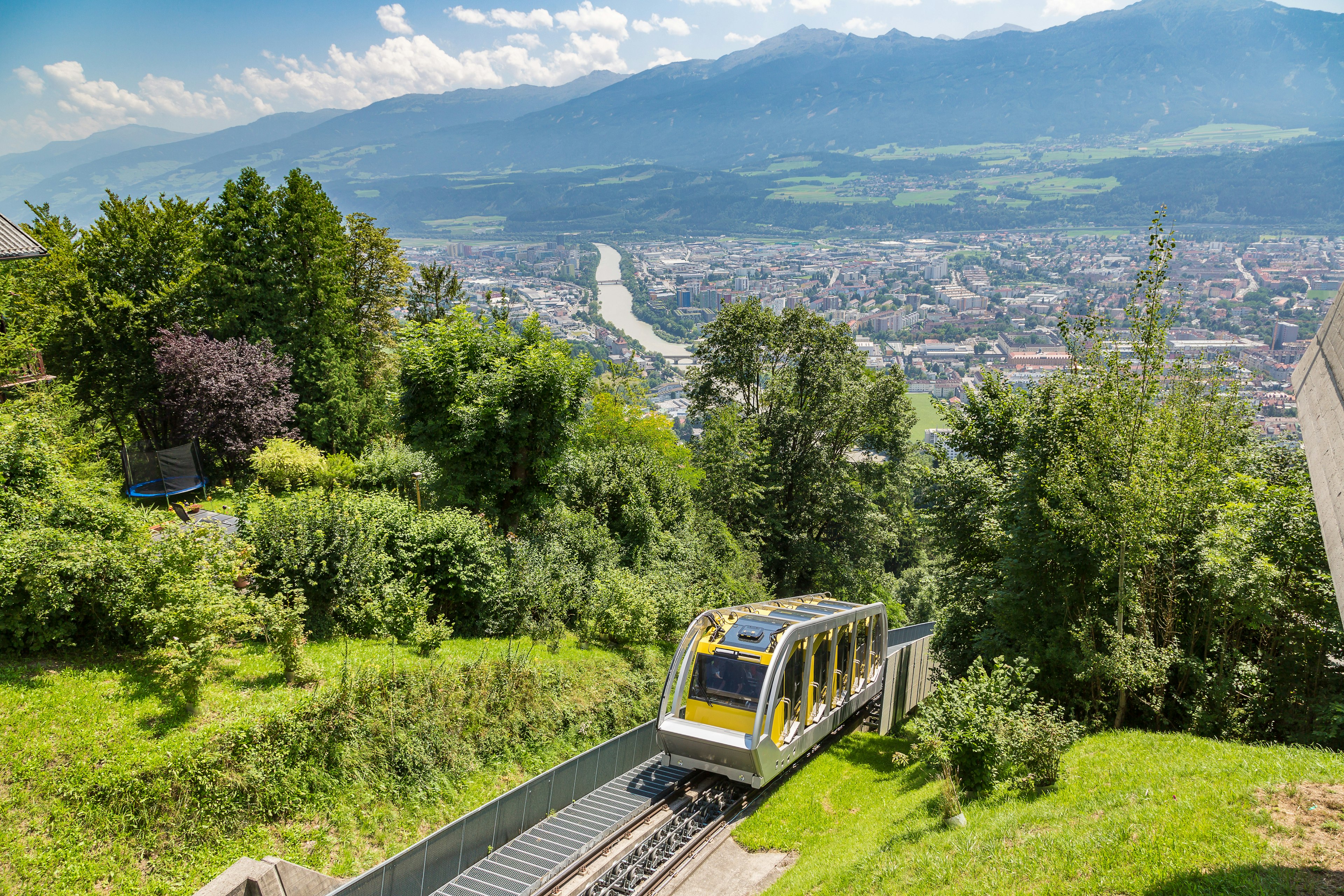 A yellow mountain railway carriage heads up a steep incline