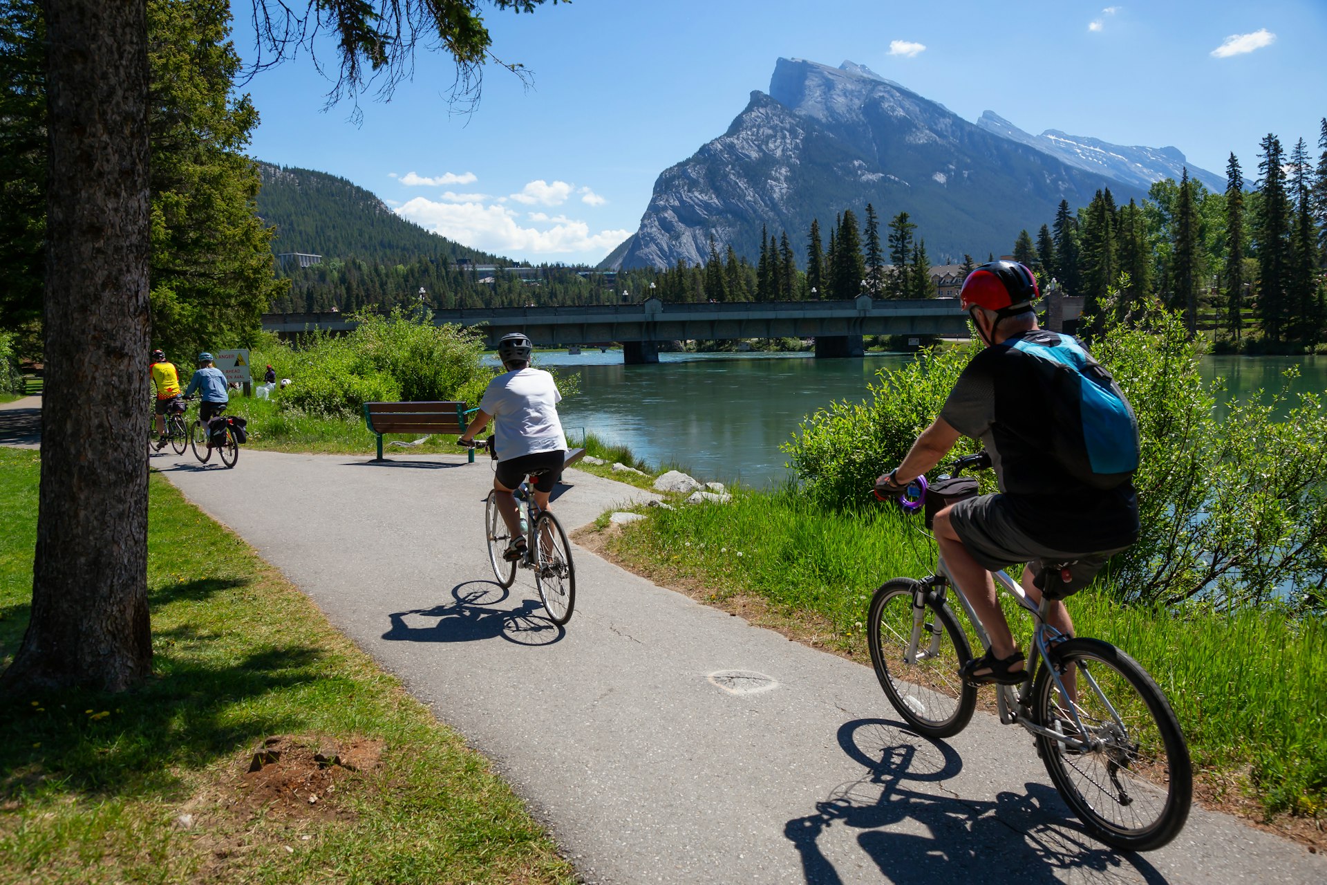 Cyclists riding along a riverside path on a sunny day