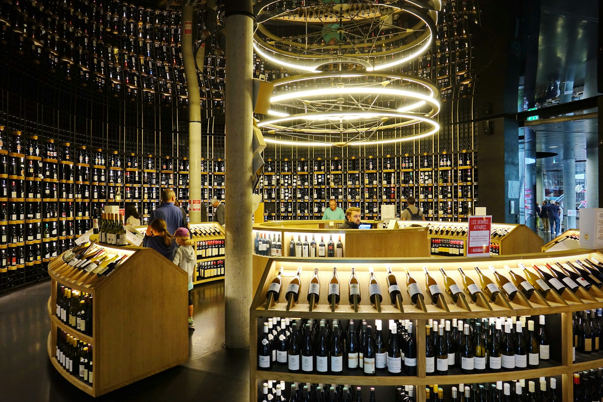 Floor-to-ceiling shelving displays hundreds of wine bottles for sale in the shop inside La Cité du Vin wine museum.