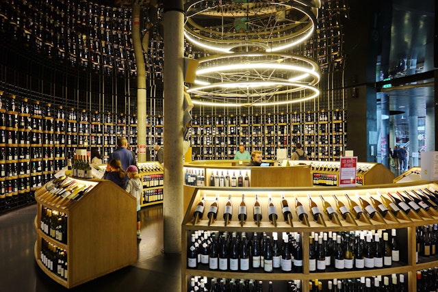 Floor-to-ceiling shelving displays hundreds of wine bottles for sale in the shop inside La Cité du Vin wine museum.