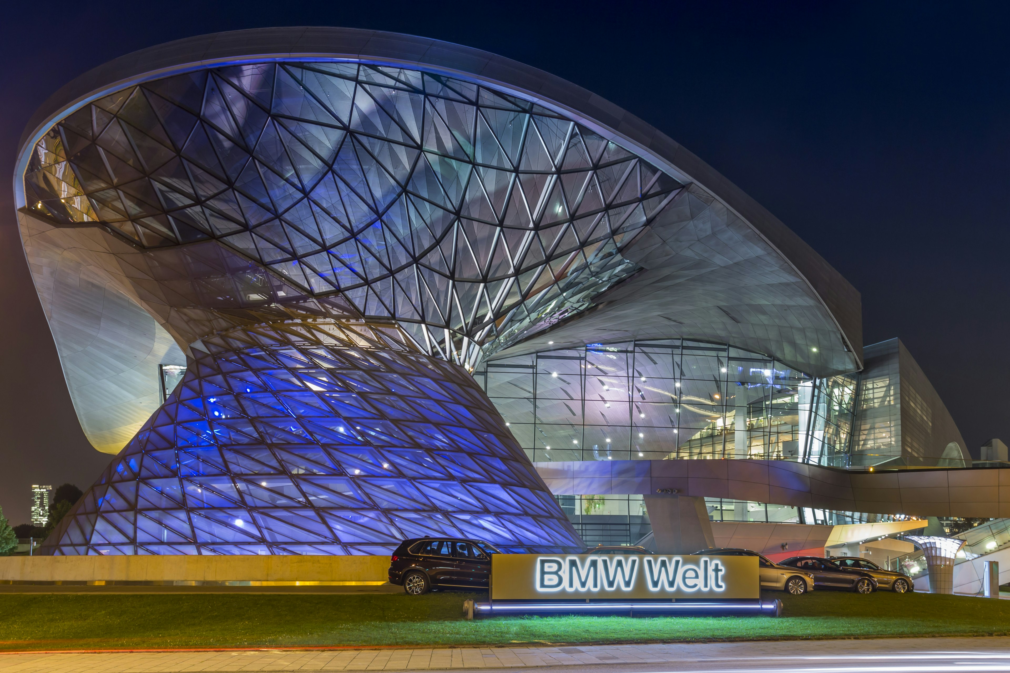 The glass and steel exterior of a car show room lit up at night