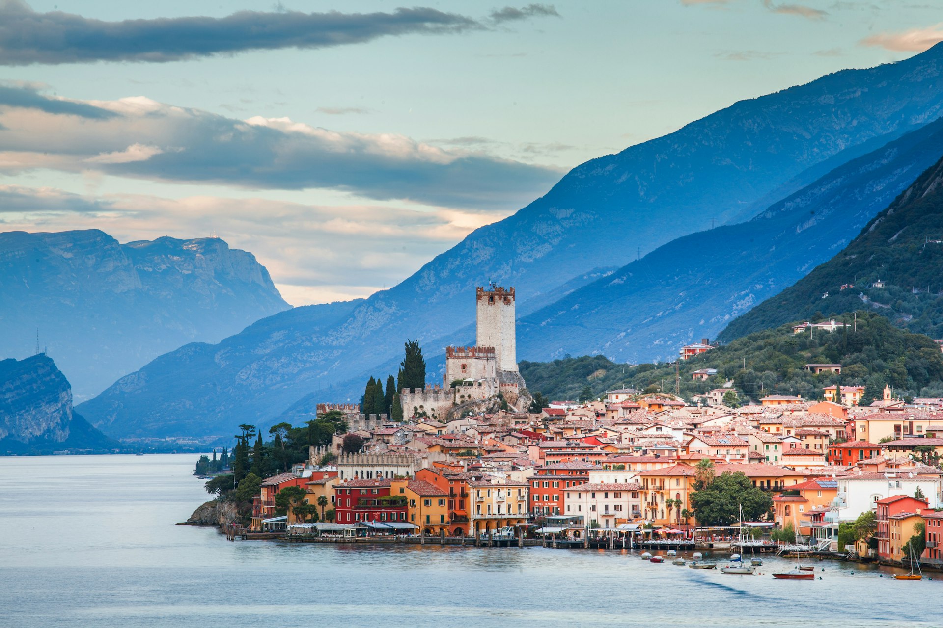 A beautiful Italian town sits on the edge of Lake Garda, with mountains in the background. 