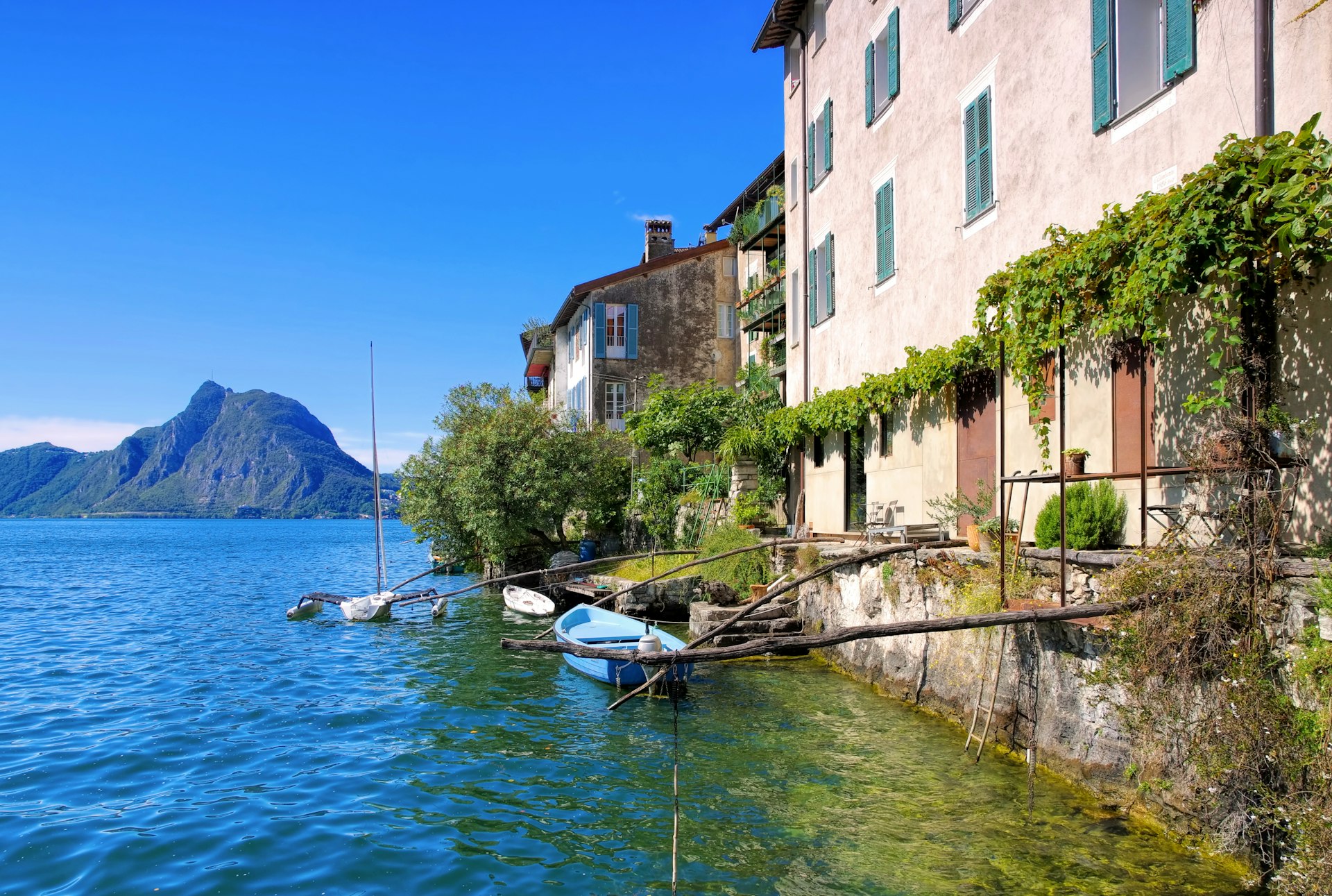 Barcos e edifícios à beira do lago na pequena aldeia de Gandria, no Lago Lugano.