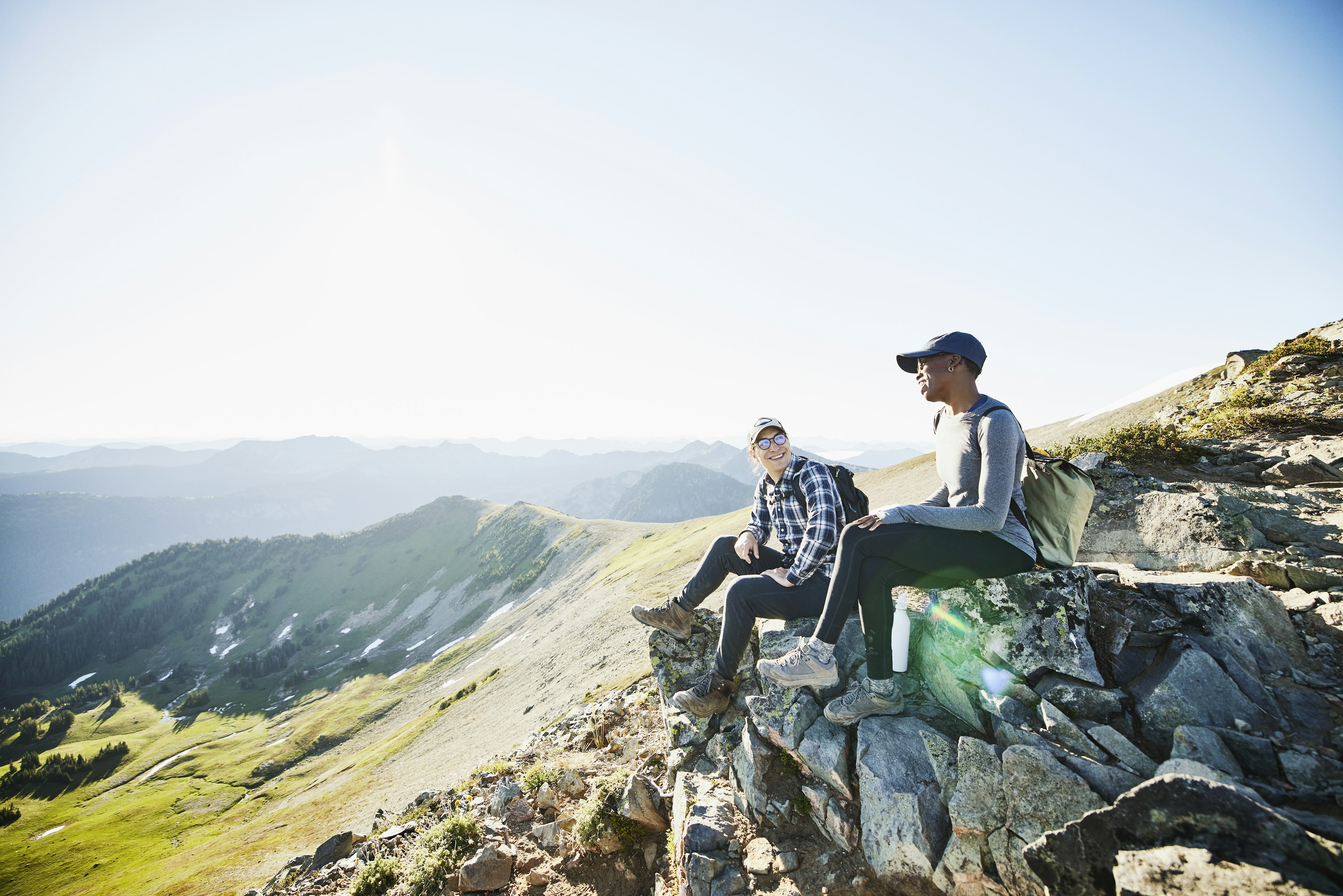 Smiling couple hanging out on rocks during early morning hike in mountains