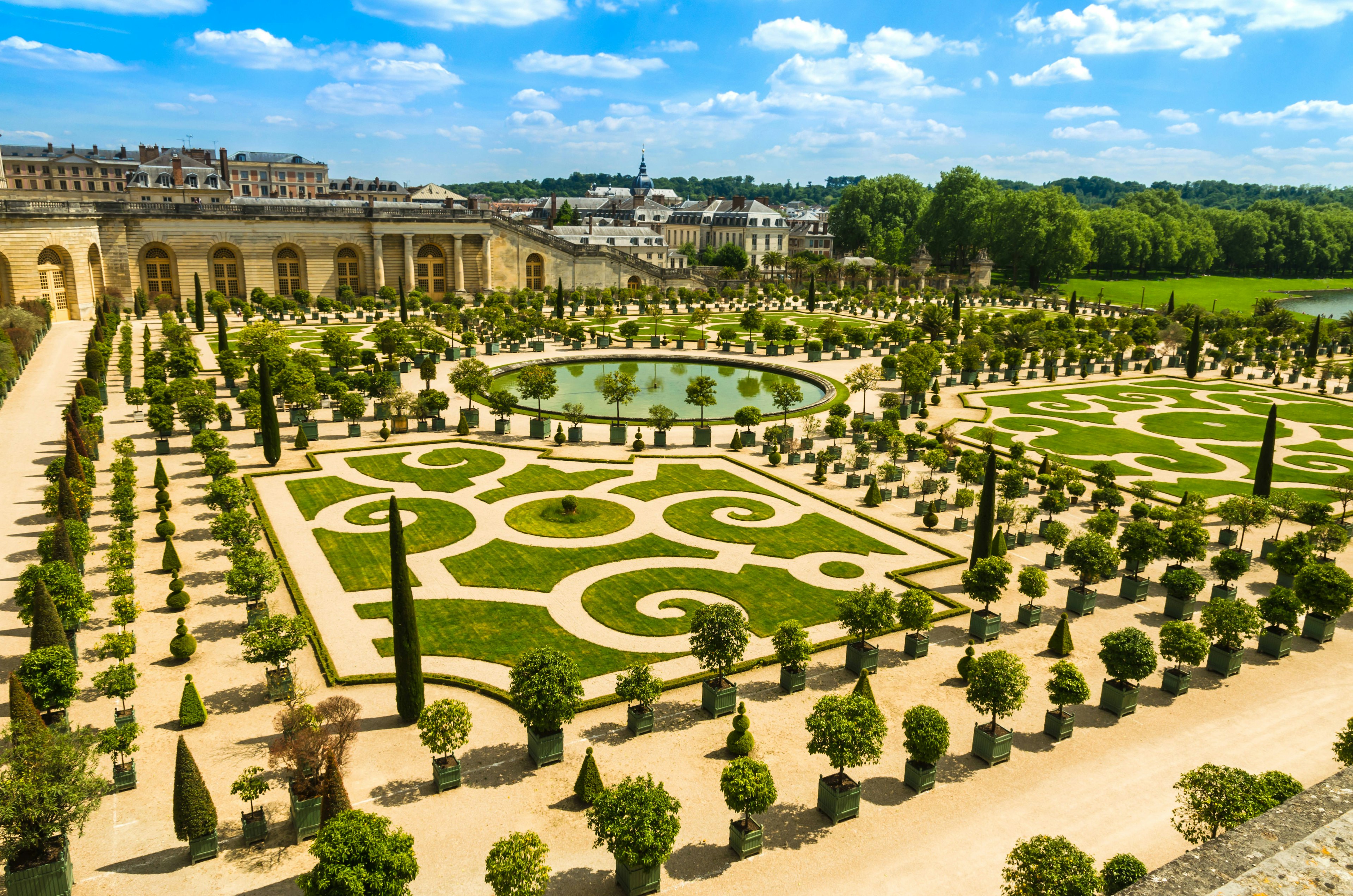 High-angle view of the manicured gardens at the Palace of Versailles, with decorative topiary and water features