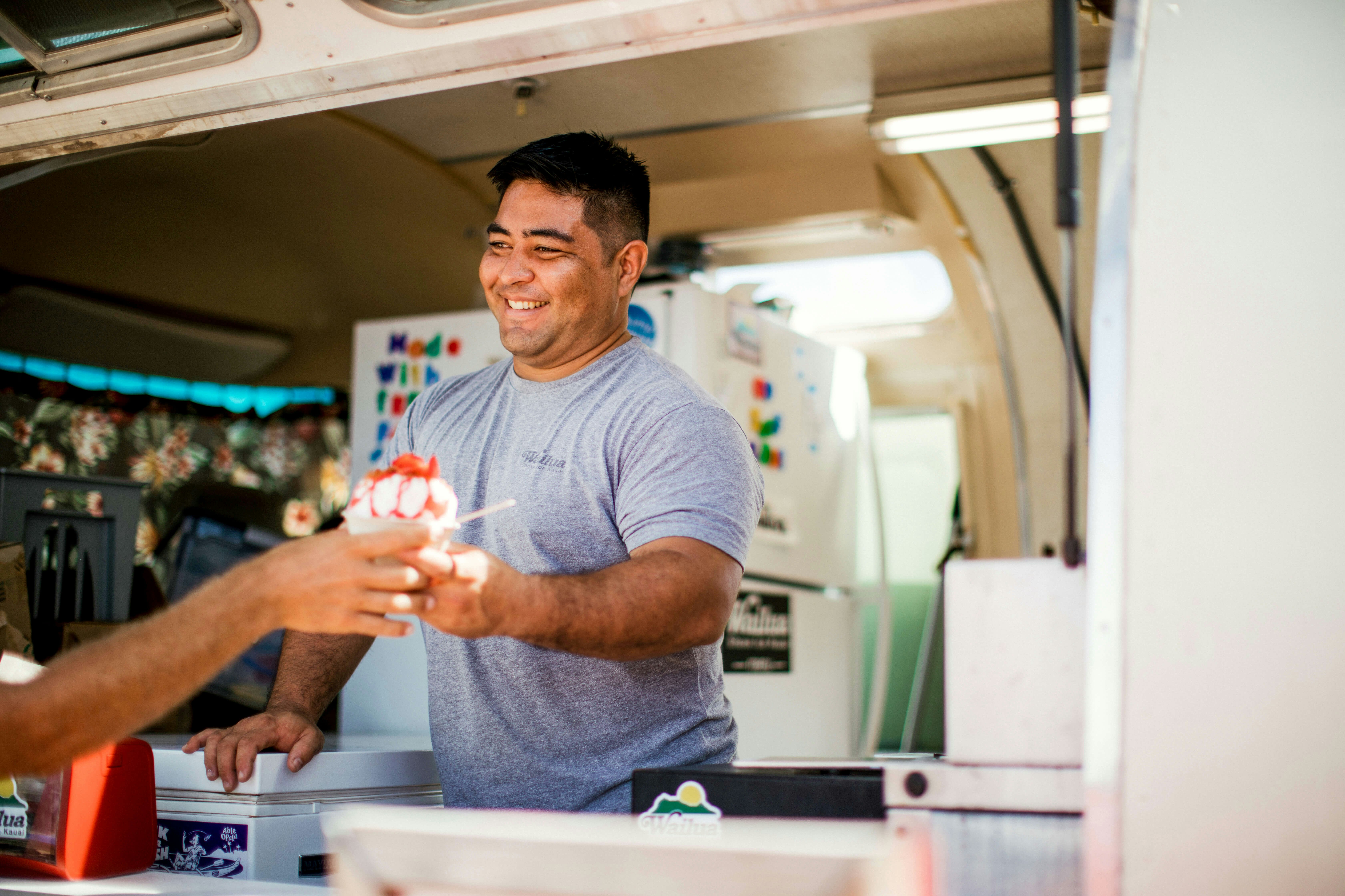 Chef Brandon Baptiste hands shave ice to customer Kauai