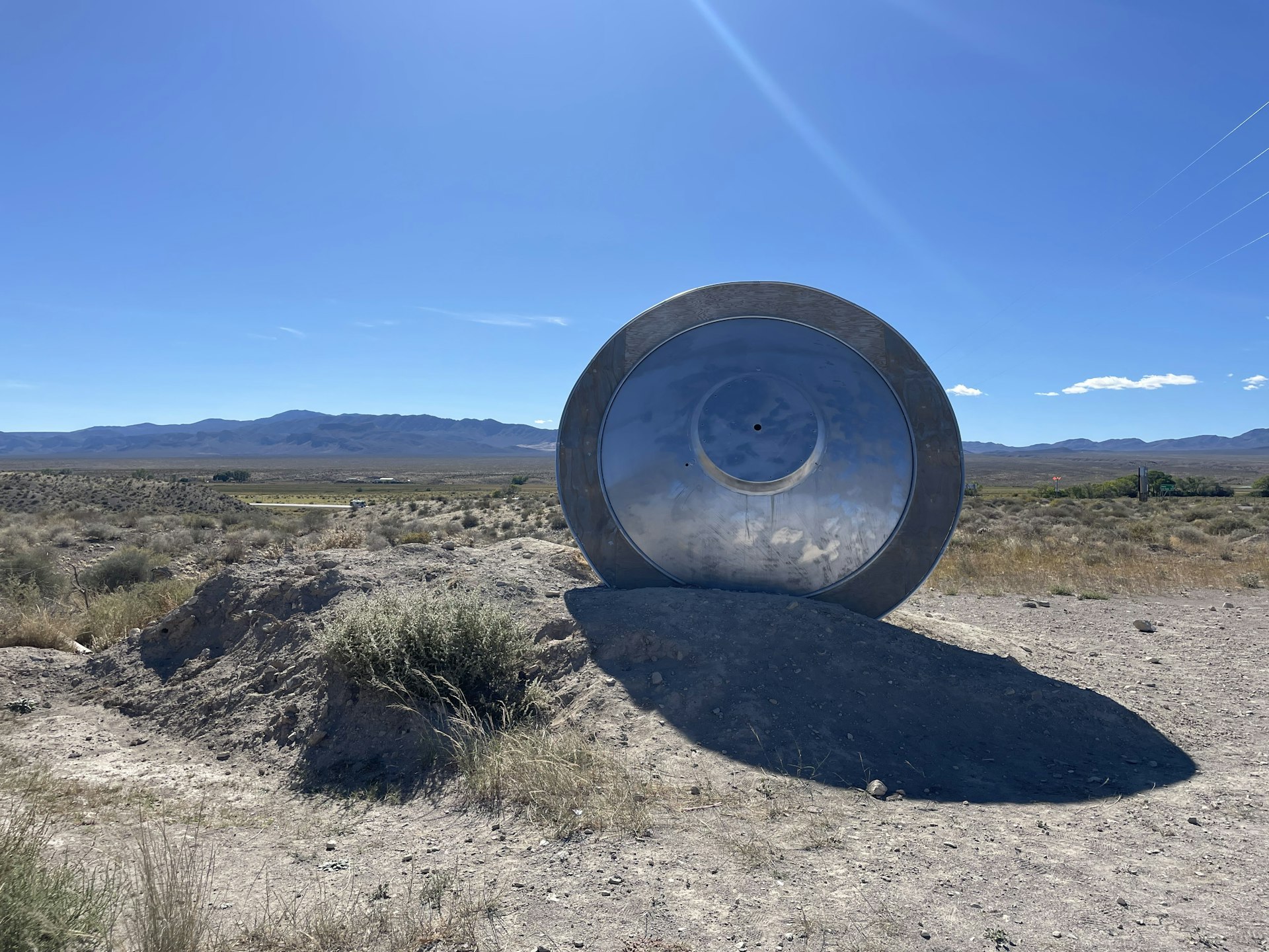 A large dish-shaped metal item - like a spaceship - stands in a desert area 
