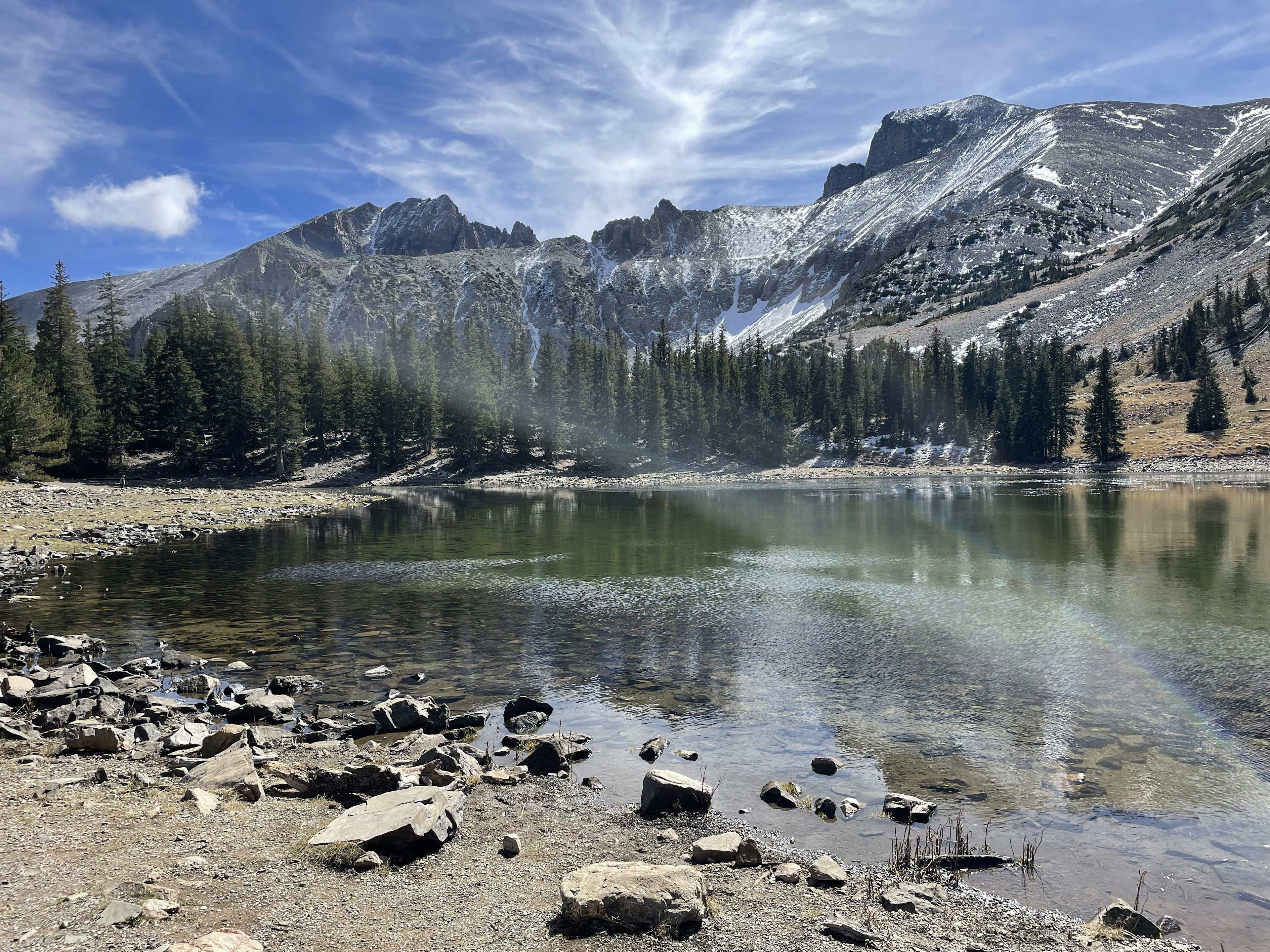 Mountains on the edge of a lake as the sun shines down