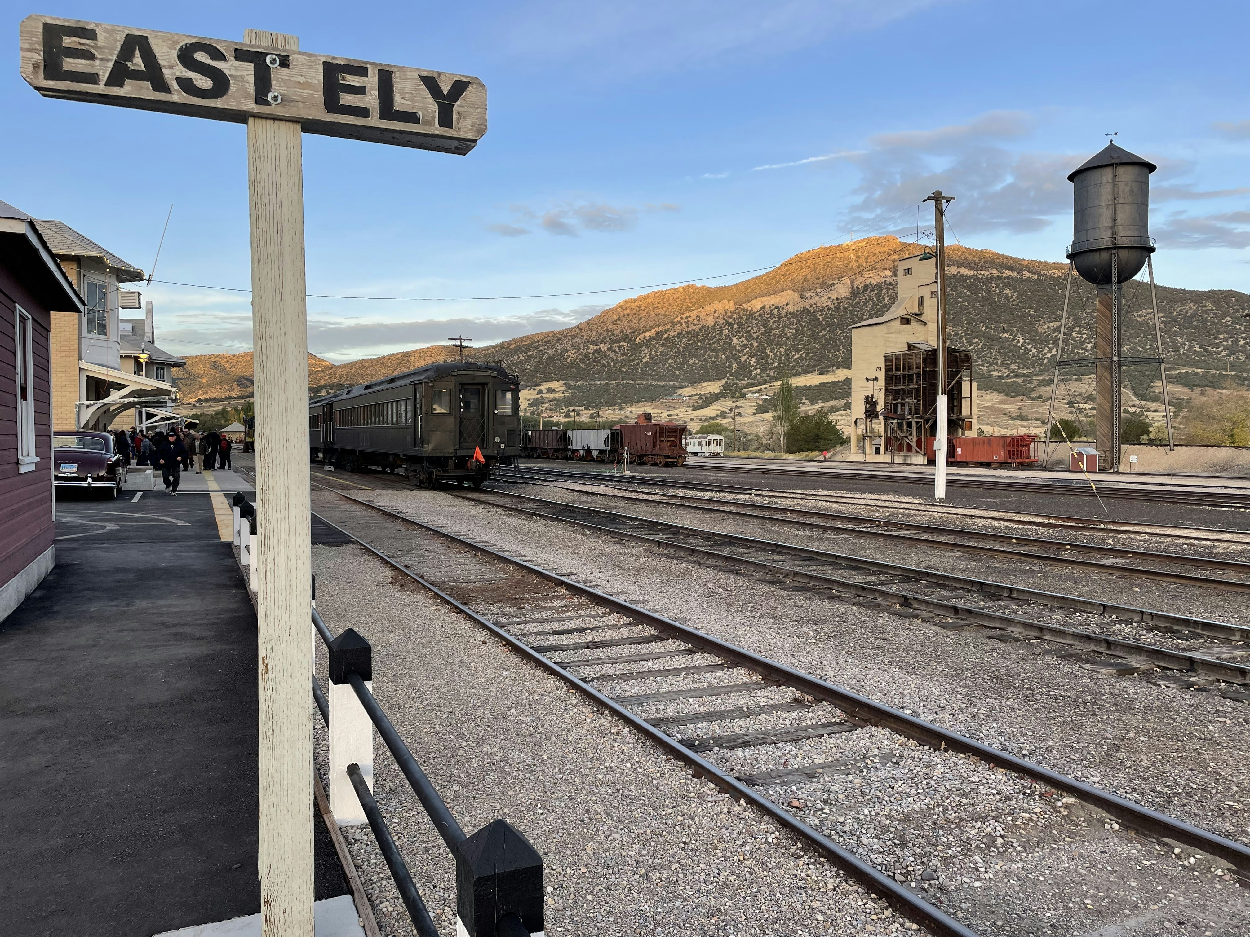 A vintage train with dark carriages passes through a station