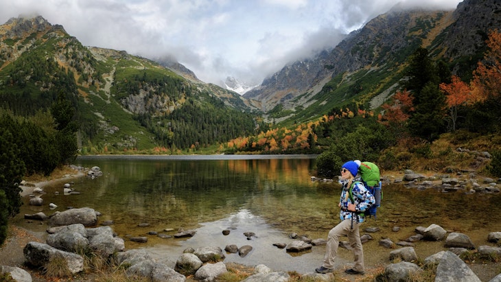 Young hiker in colorful fantastic mountain landscape at gold autumn near Popradske Pleso lake in High Tatras