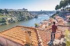 1063875272
A man standing on a rooftop terrace and admiring Porto and Dom Luis I bridge