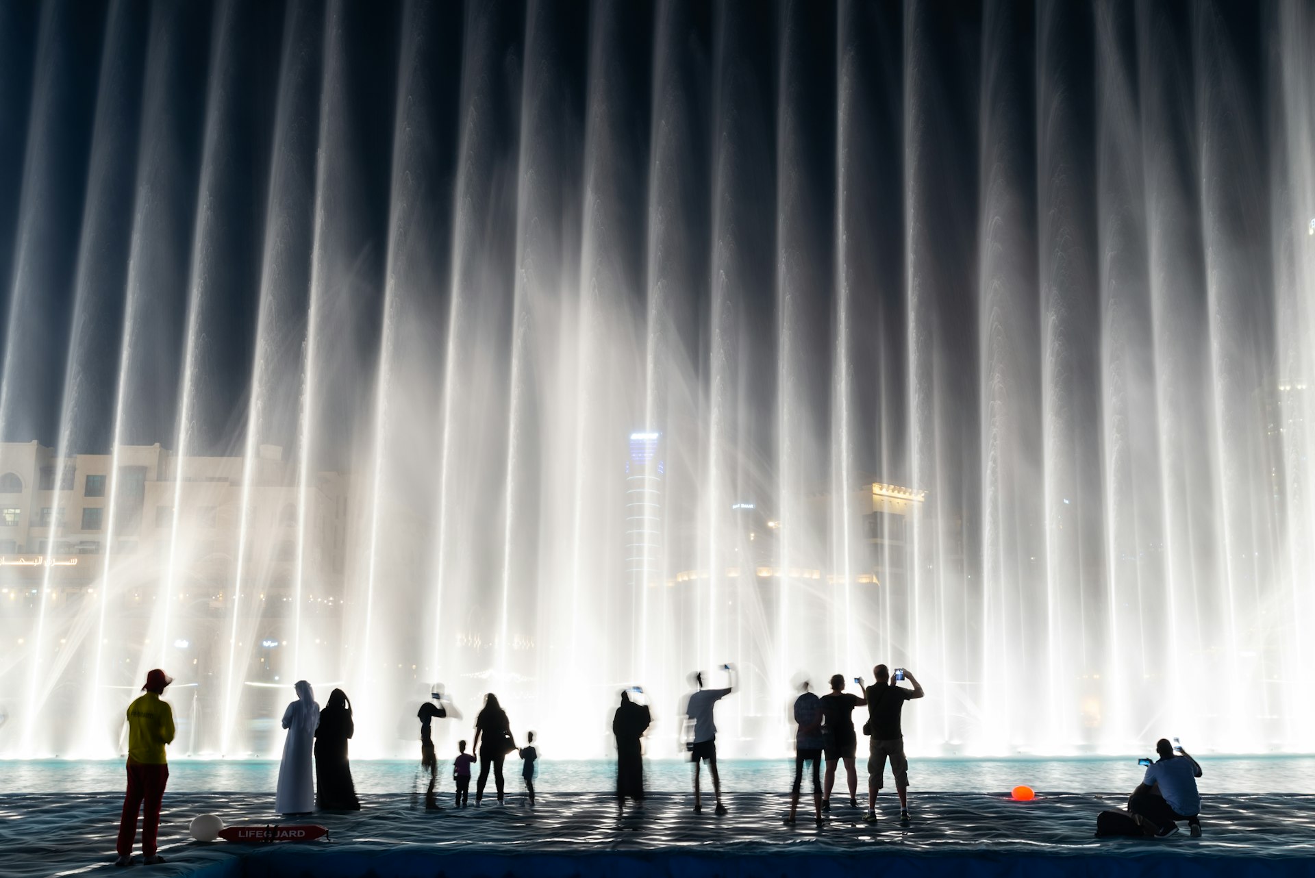 Silhouettes of people enjoying the fountain show in Dubai at night, UAE 
