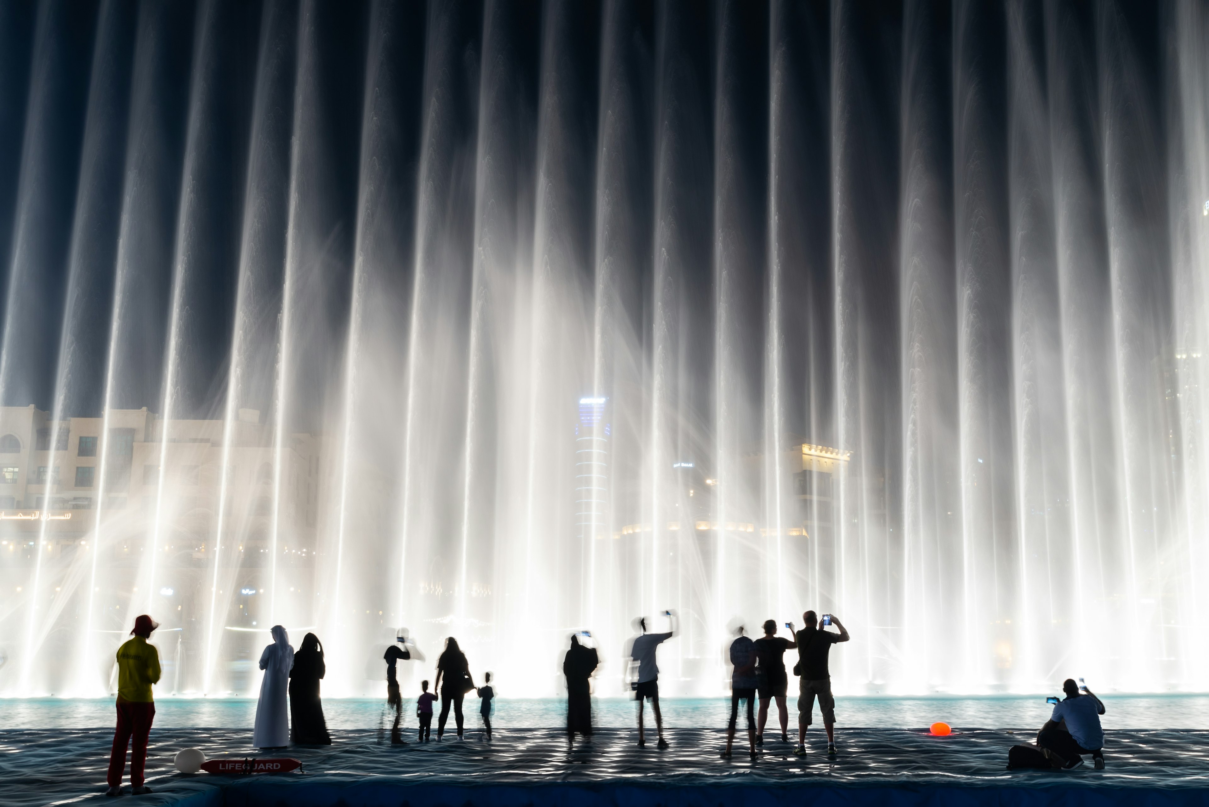 Silhouettes of people enjoying the fountain show in Dubai at night, UAE