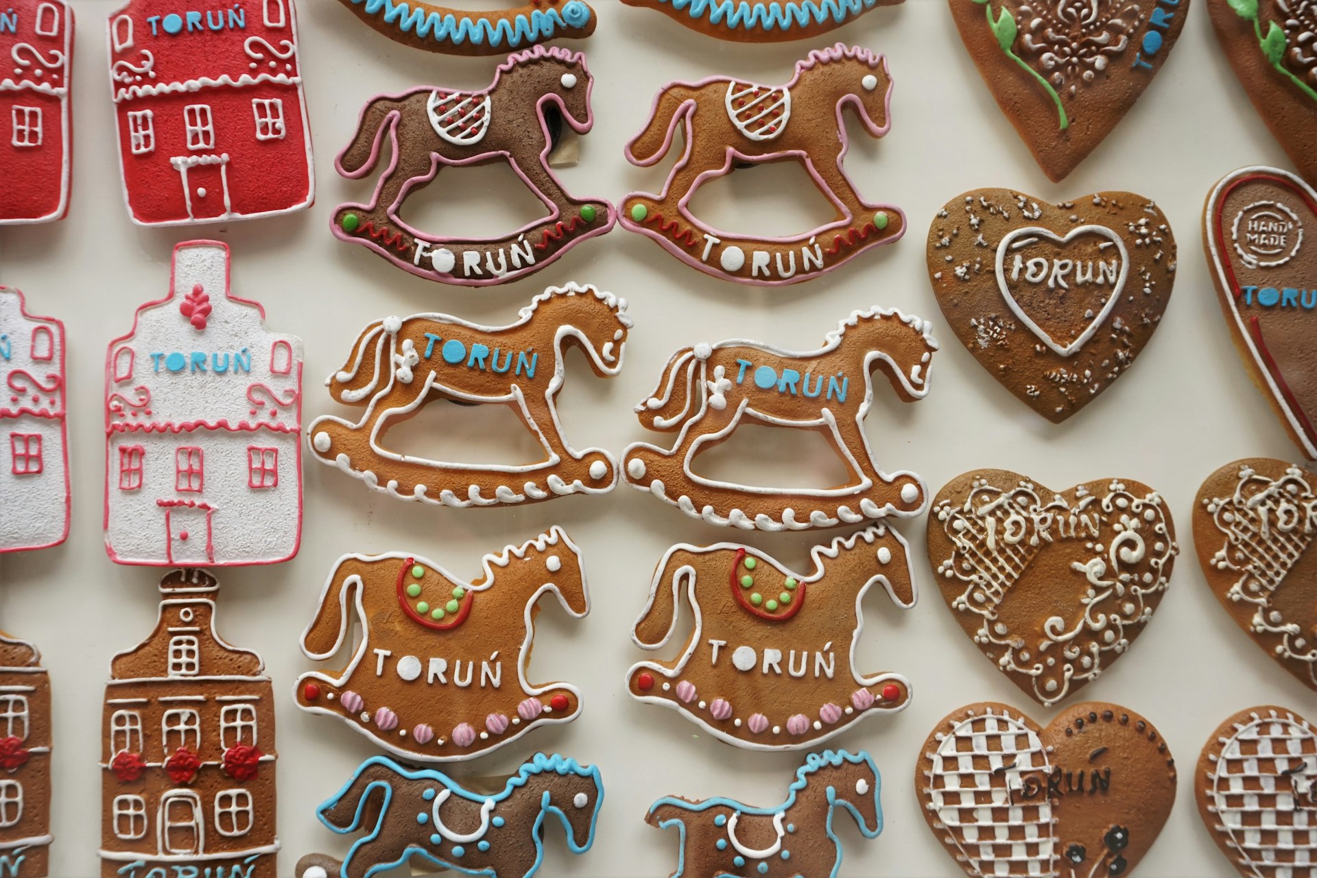 A display of decorated gingerbread cookies in the shape of rocking horses, love hearts and houses.