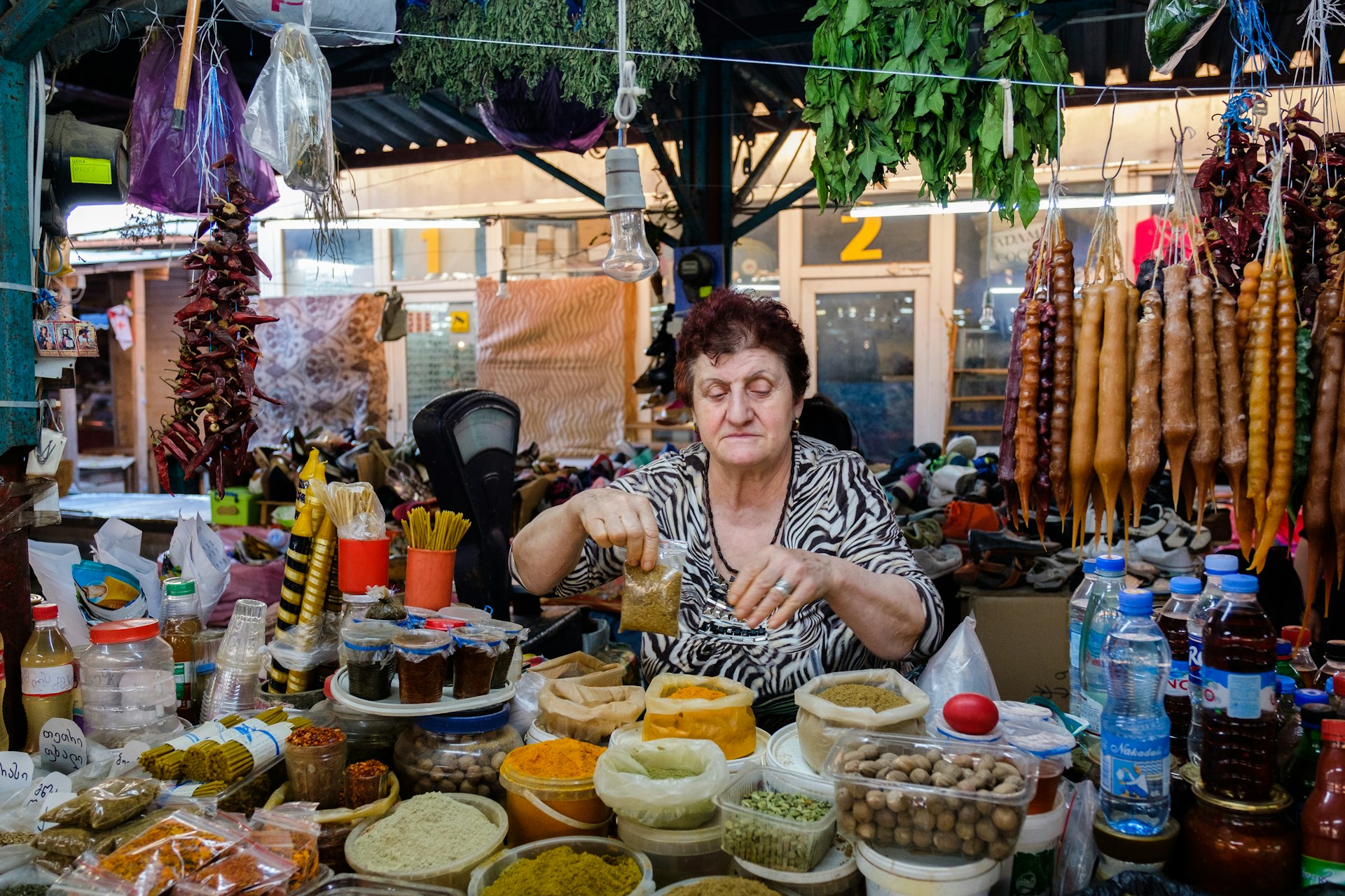 A senior woman is packaging up spices in a market stall in Kutaisi, Georgia