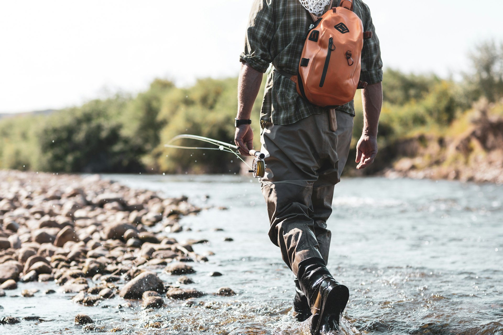 Homem carregando equipamento ao longo da pesca com mosca no rio em Wyoming, EUA
