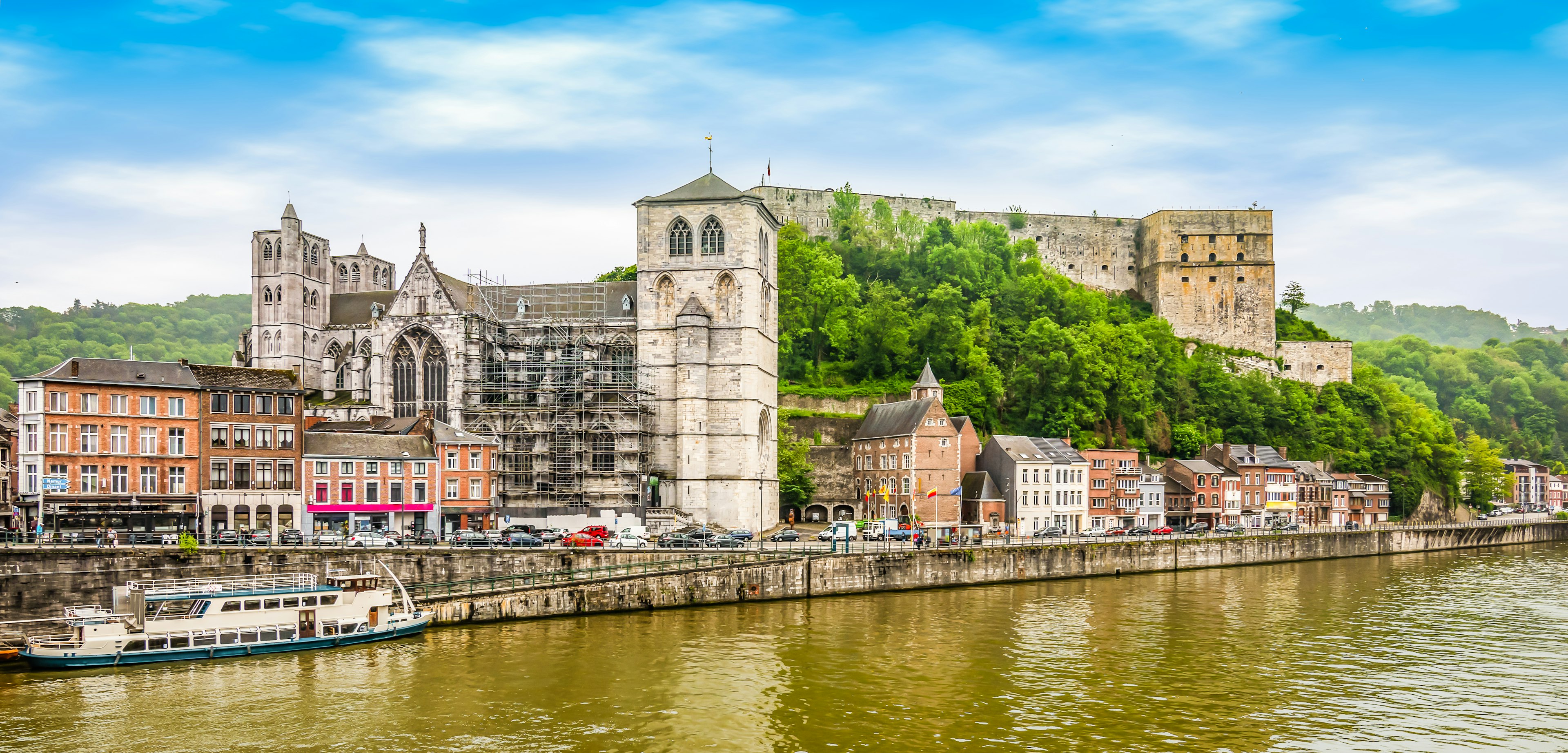 A fortress sits on a hilltop overlooking a riverside town