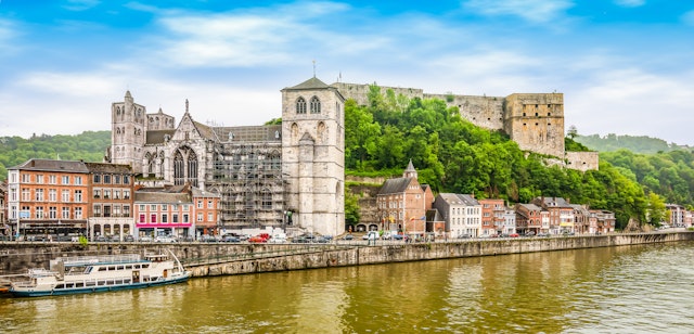 A fortress sits on a hilltop overlooking a riverside town