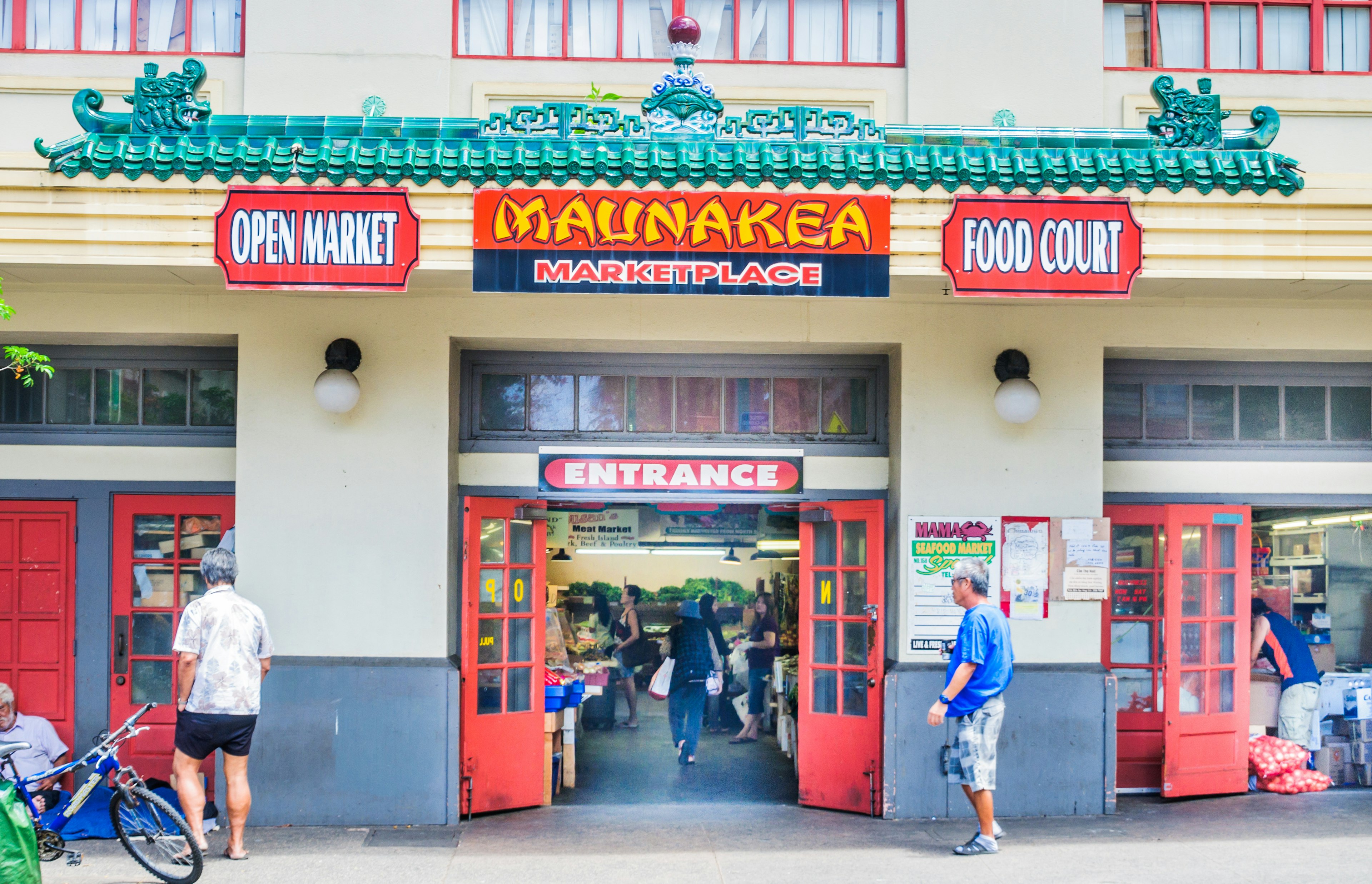 The exterior of a white building with red signs that say