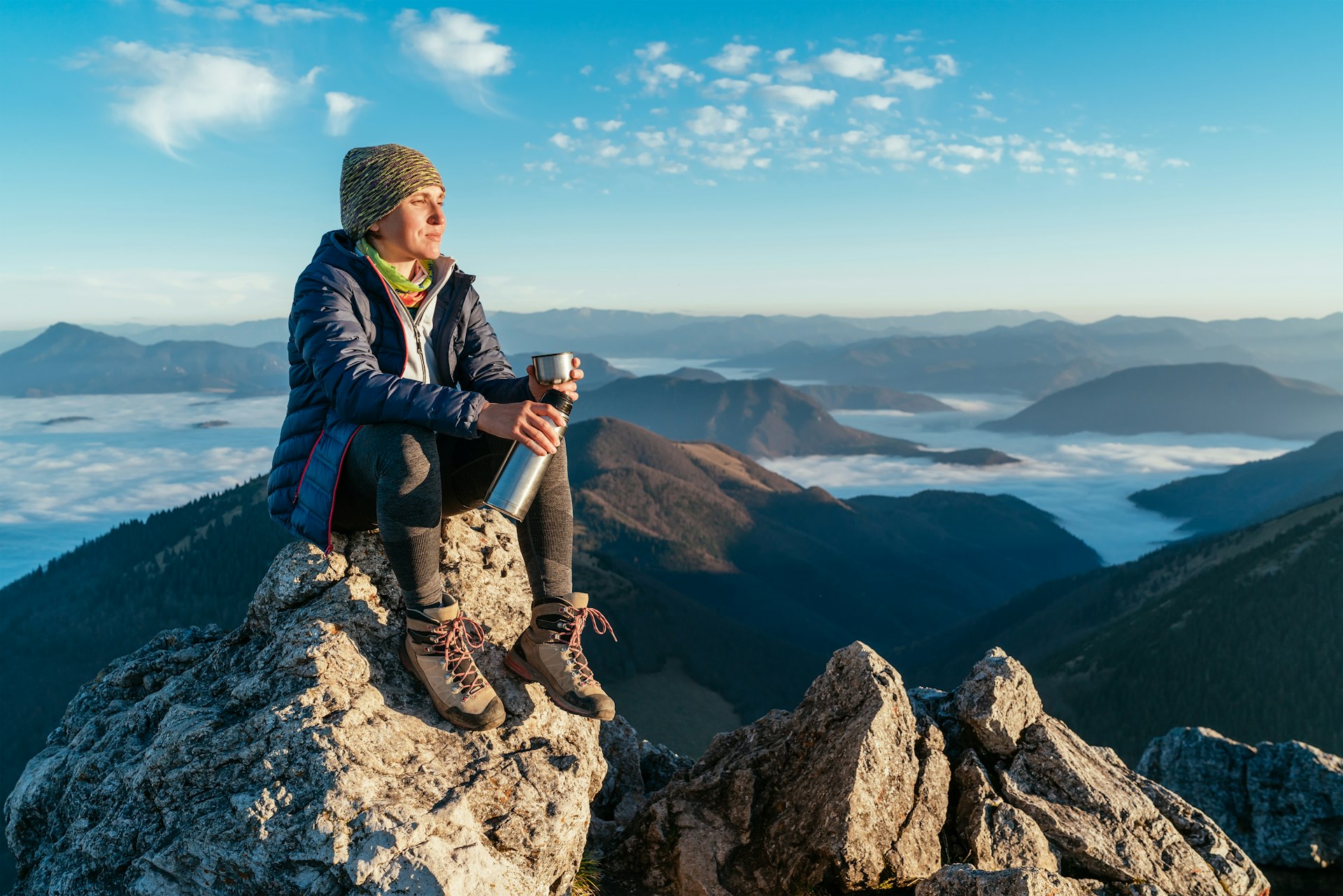 A young hiker atop a mountain summit overlooking the clouds in Slovakia
