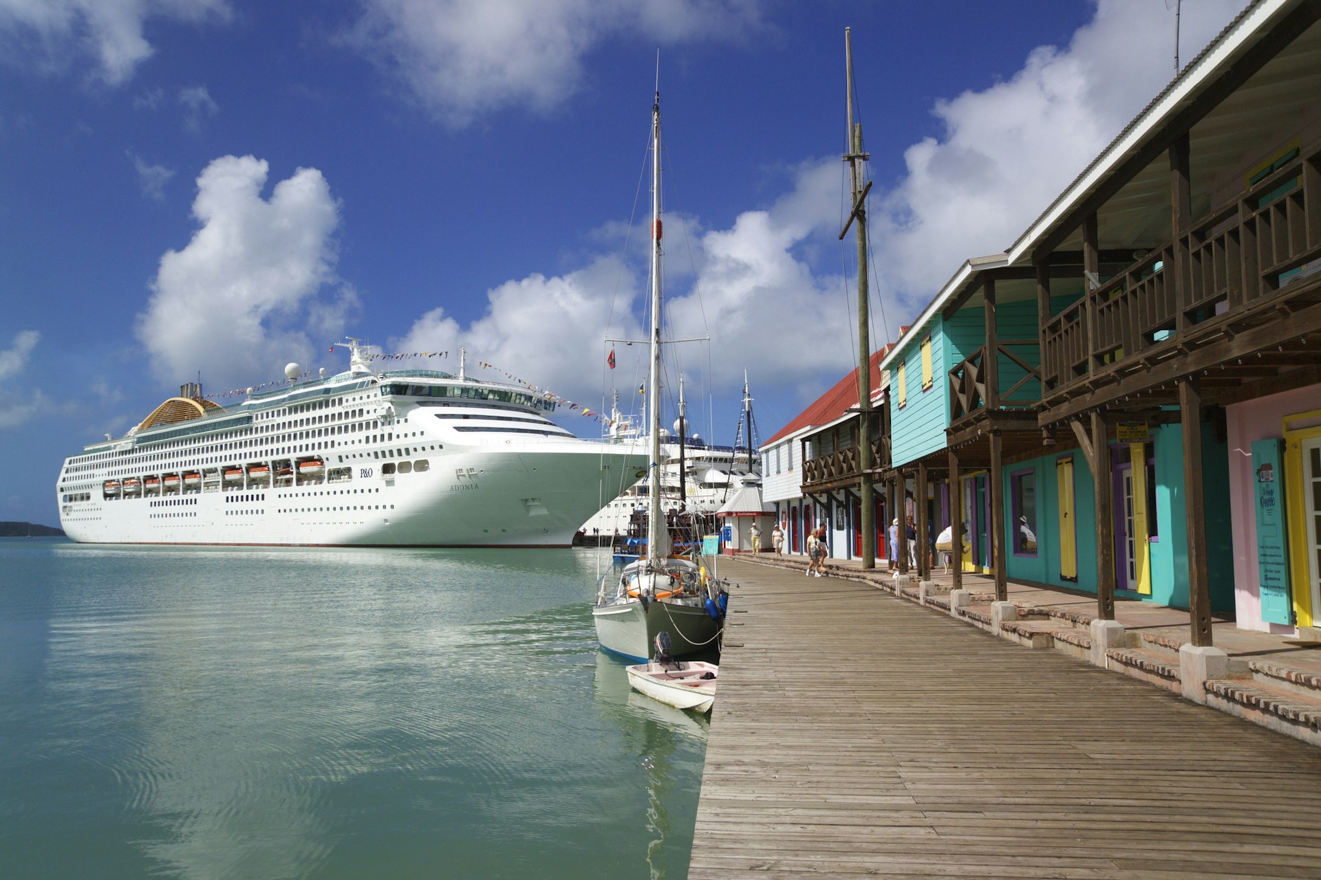 A cruise ship docking at a pier with colorful wooden buildings