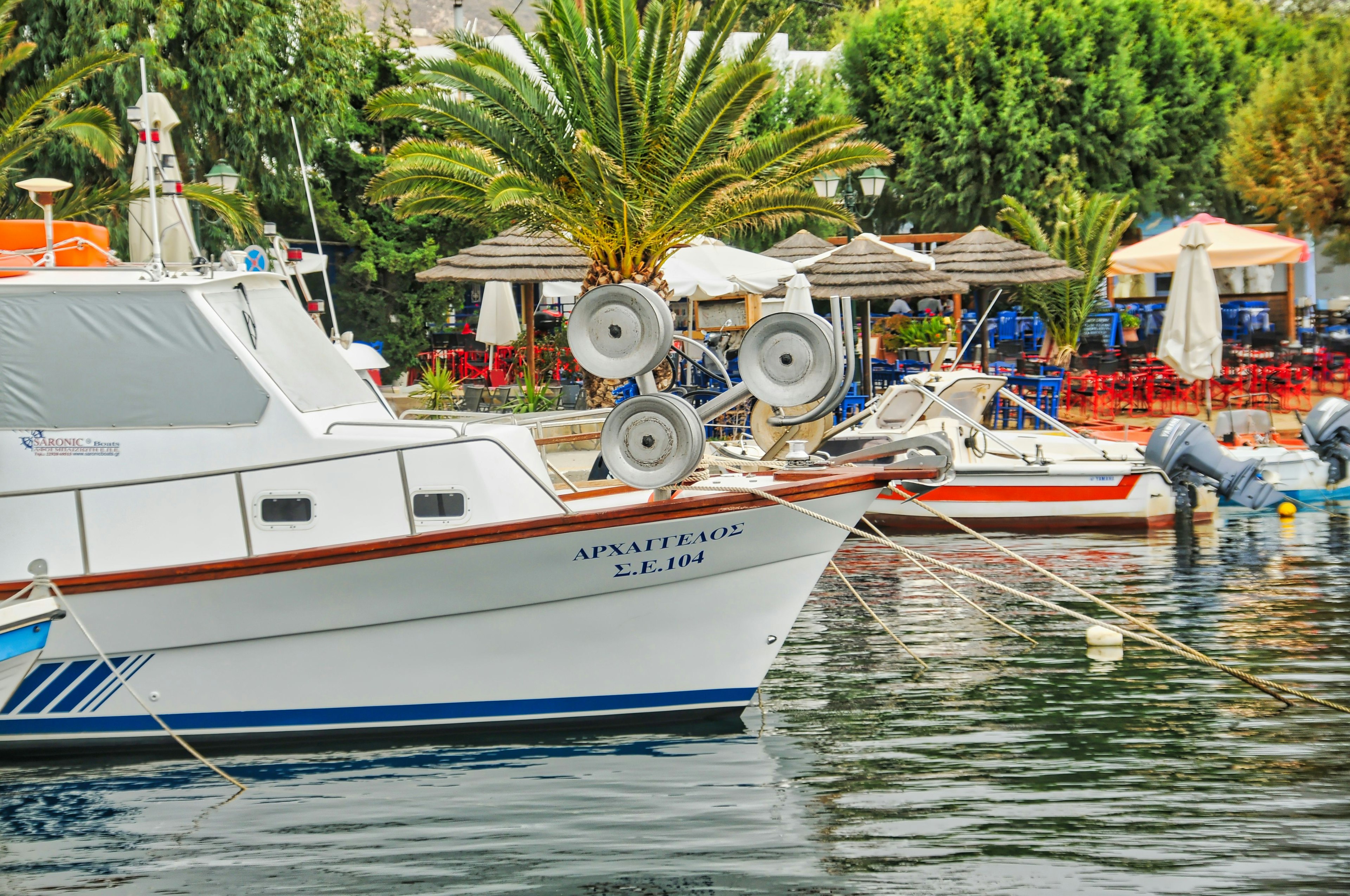 Fishing boats by the dock in Livadi village, Serifos island, on a sunny day with a blue sky