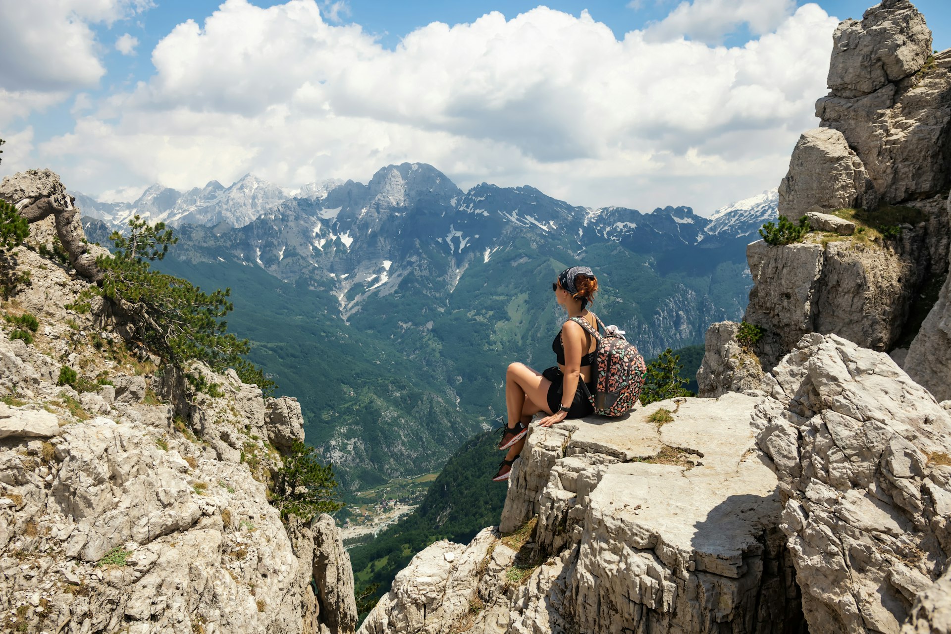 A woman sits on the edge of a hiking trail in the Albanian mountains