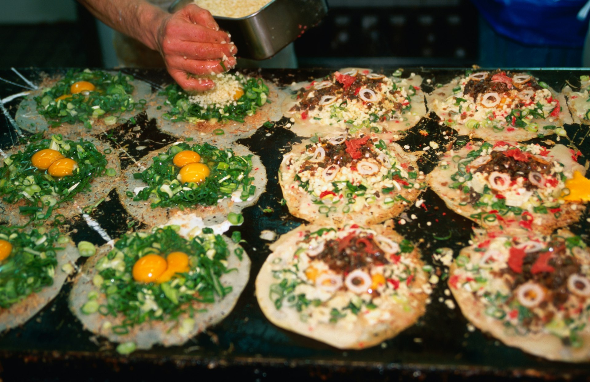 A chef preparing cabbage-based omelettes on a hot plate