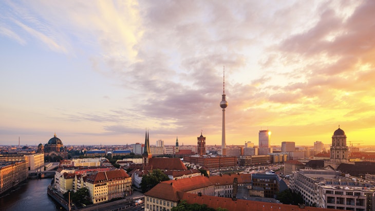 A view of the Berlin at sunrise showing the iconic TV tower, rooftops, and the river Spree
