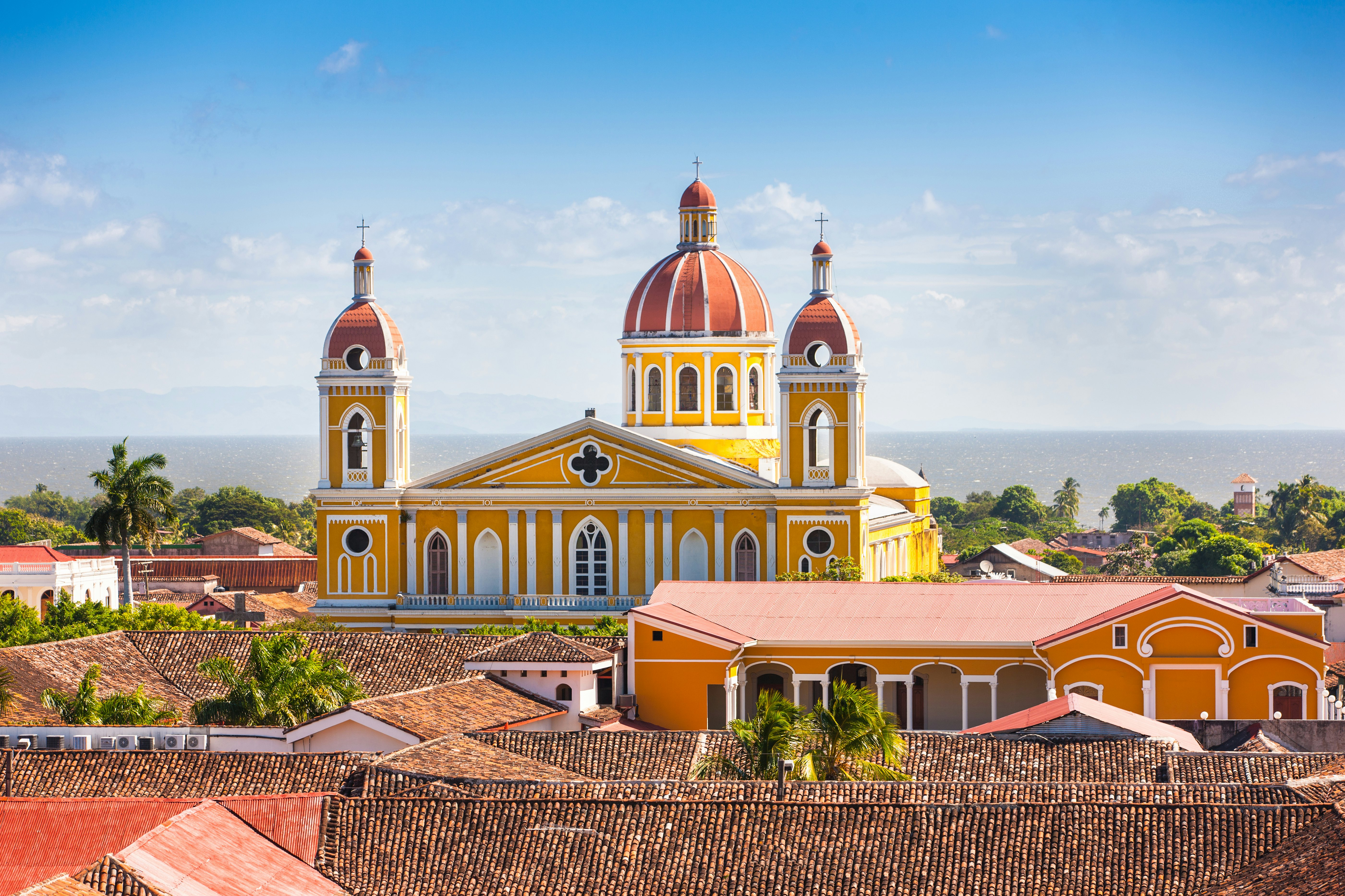 A yellow domed cathedral with two bell towers at the edge of the ocean