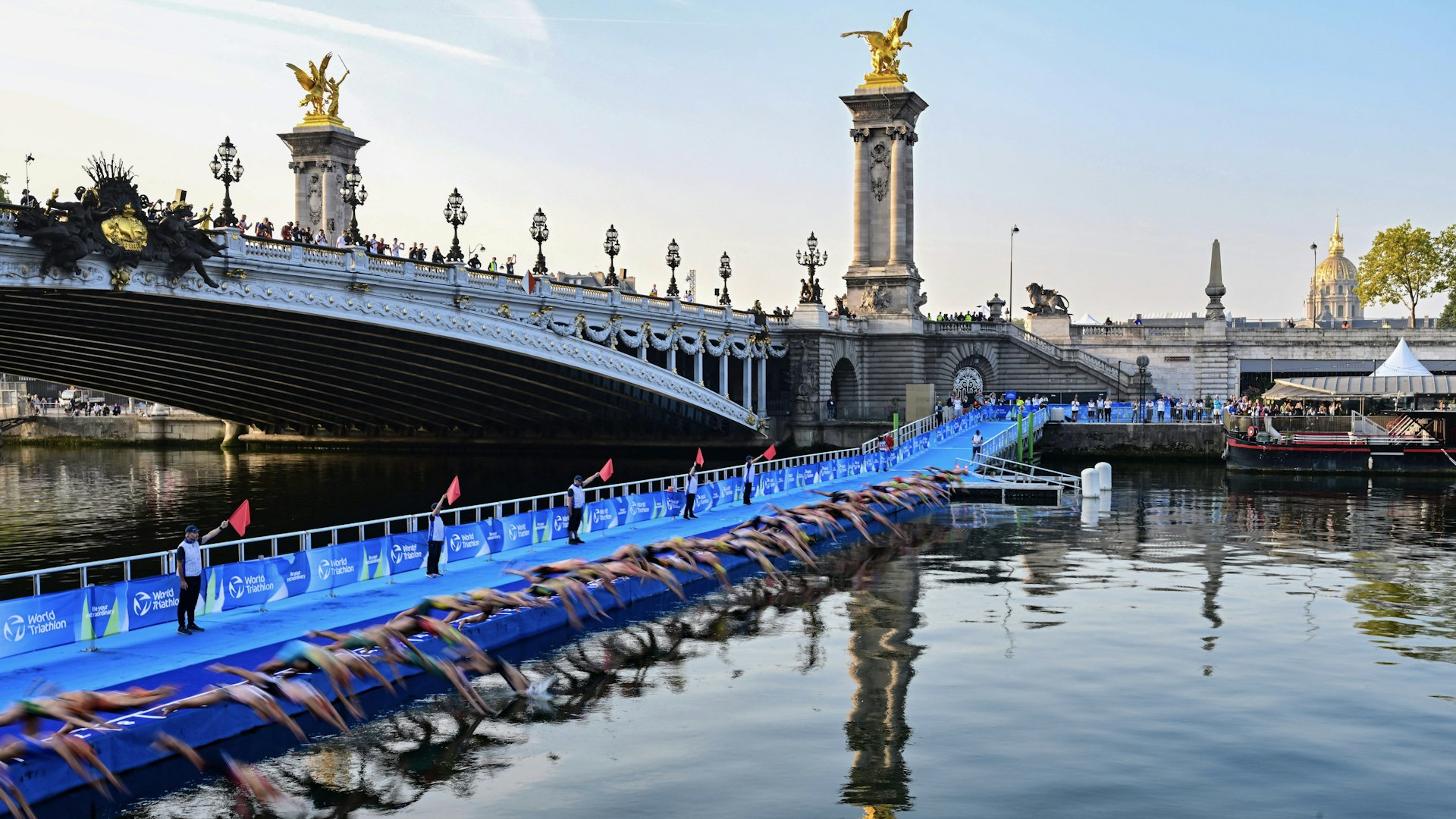 Triathlon athletes start to compete swimming in the Seine river next to the Alexandre III bridge during a Test Event for the women's triathlon