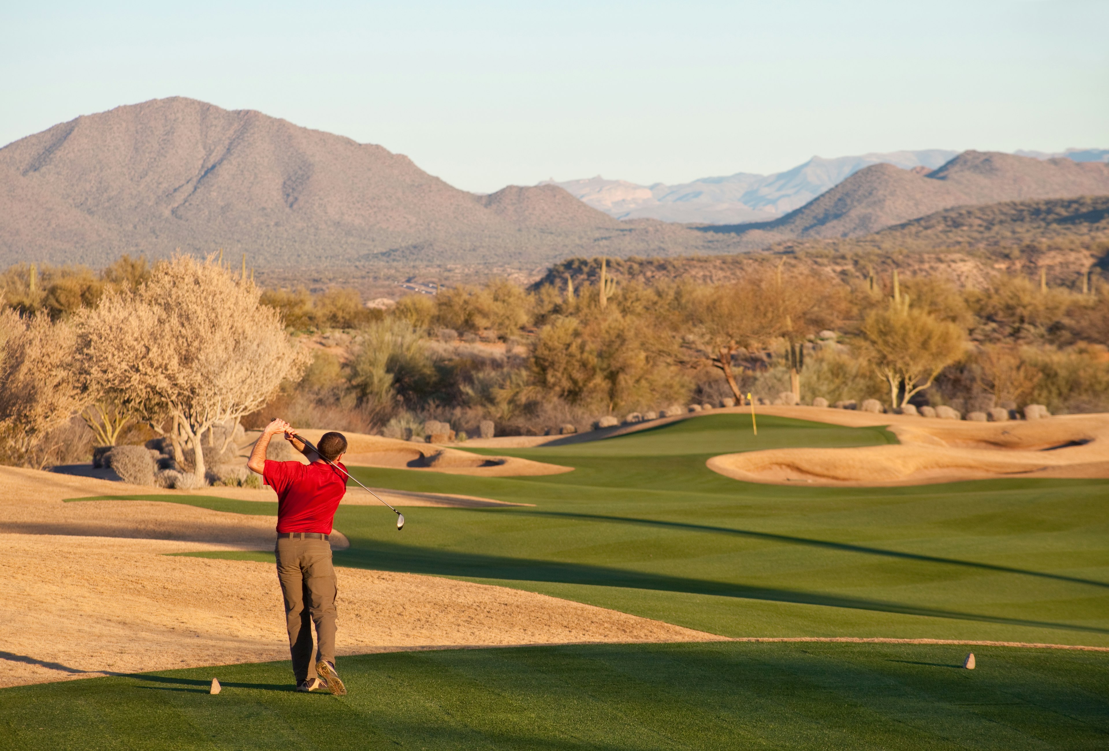 A male caucasian golfer gets ready to hit a drive on a beautiful desert golf hole. Phoenix, Arizona.